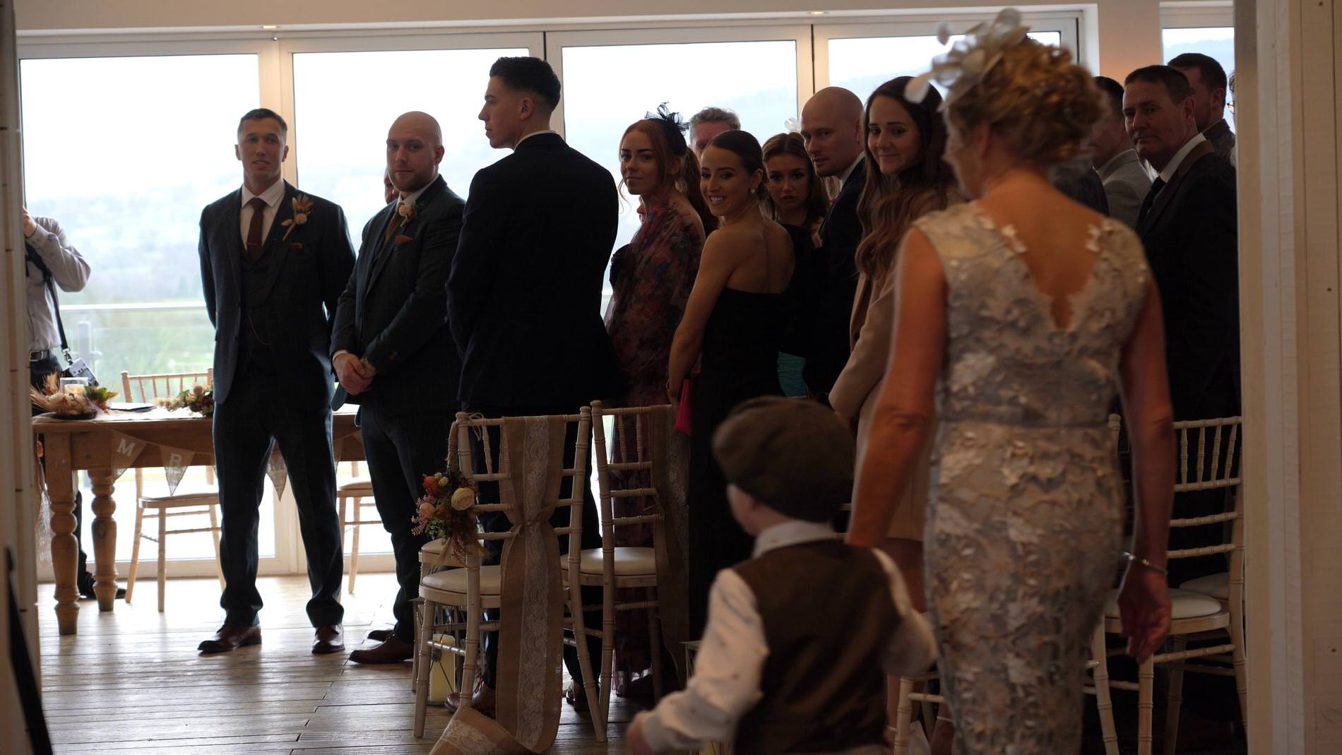 wedding guests smile as the pageboy walks down the aisle at Bashall Barn