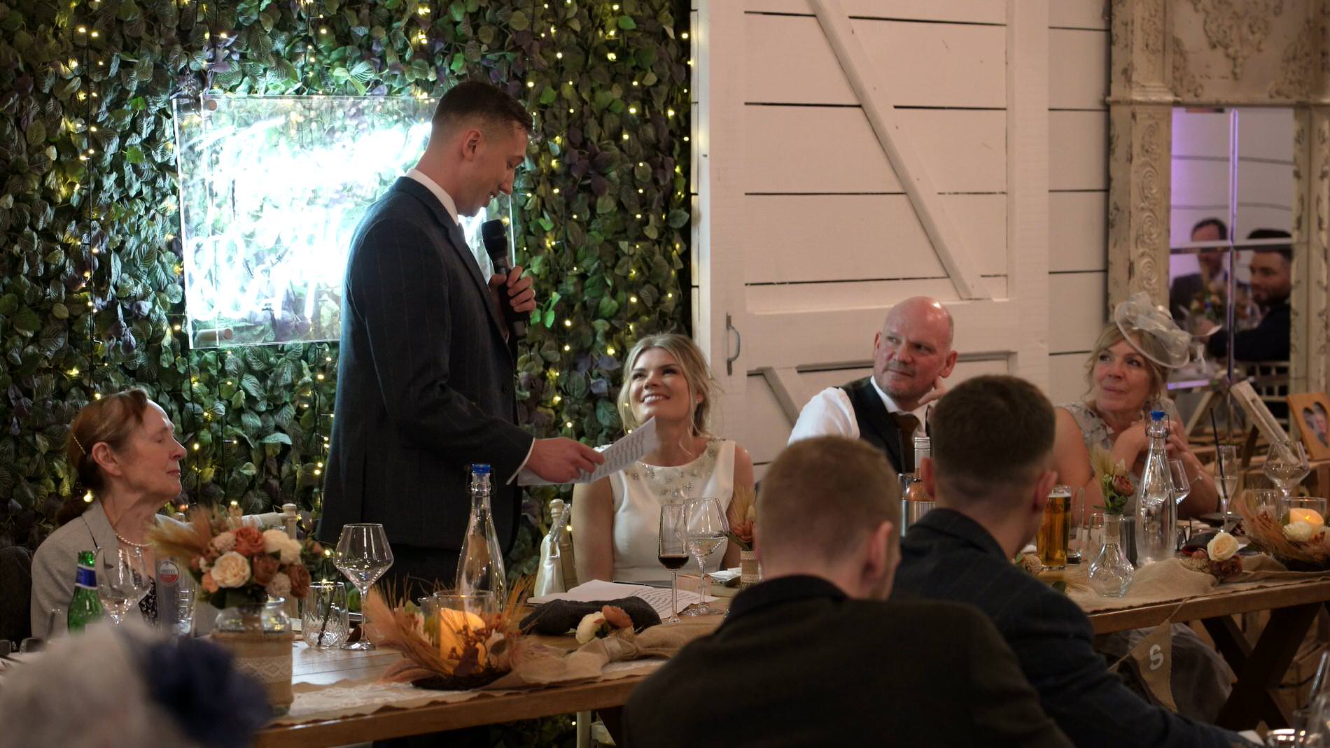 groom makes the bride smile during speech at Bashall Barn