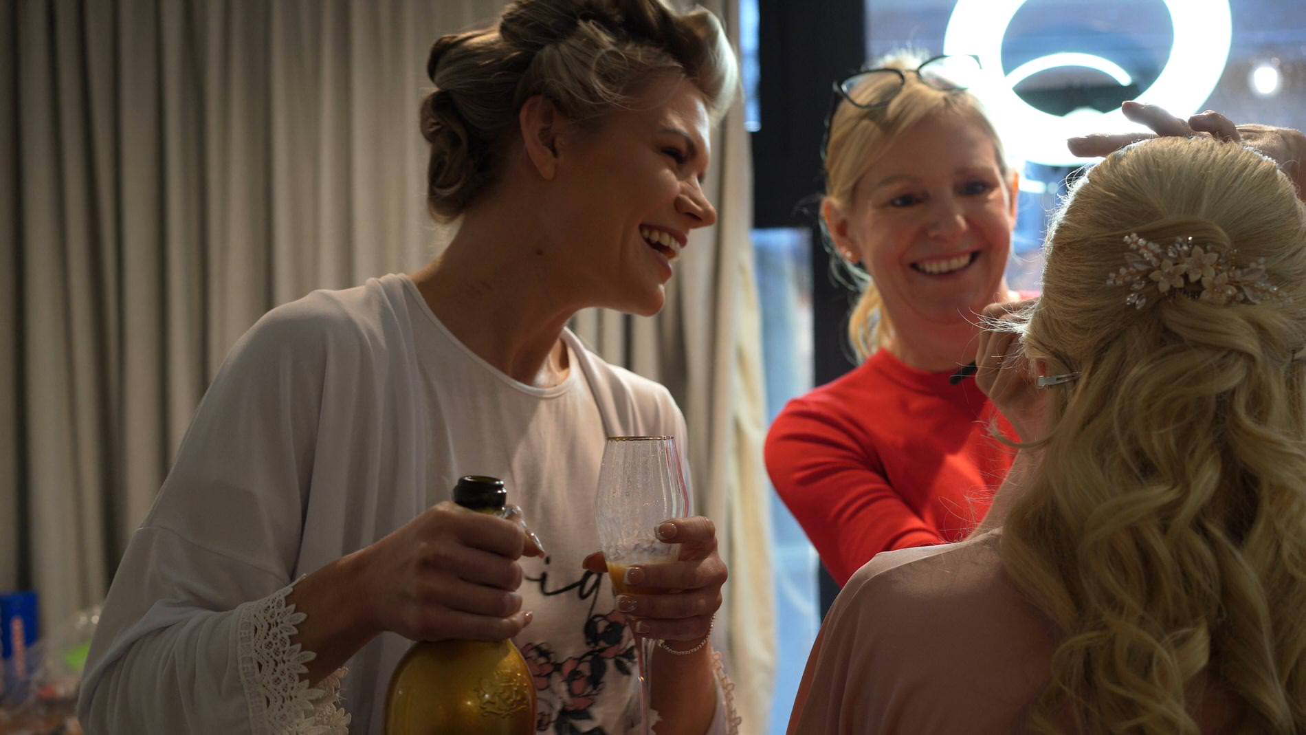 a bride laughs with her bridesmaid getting ready