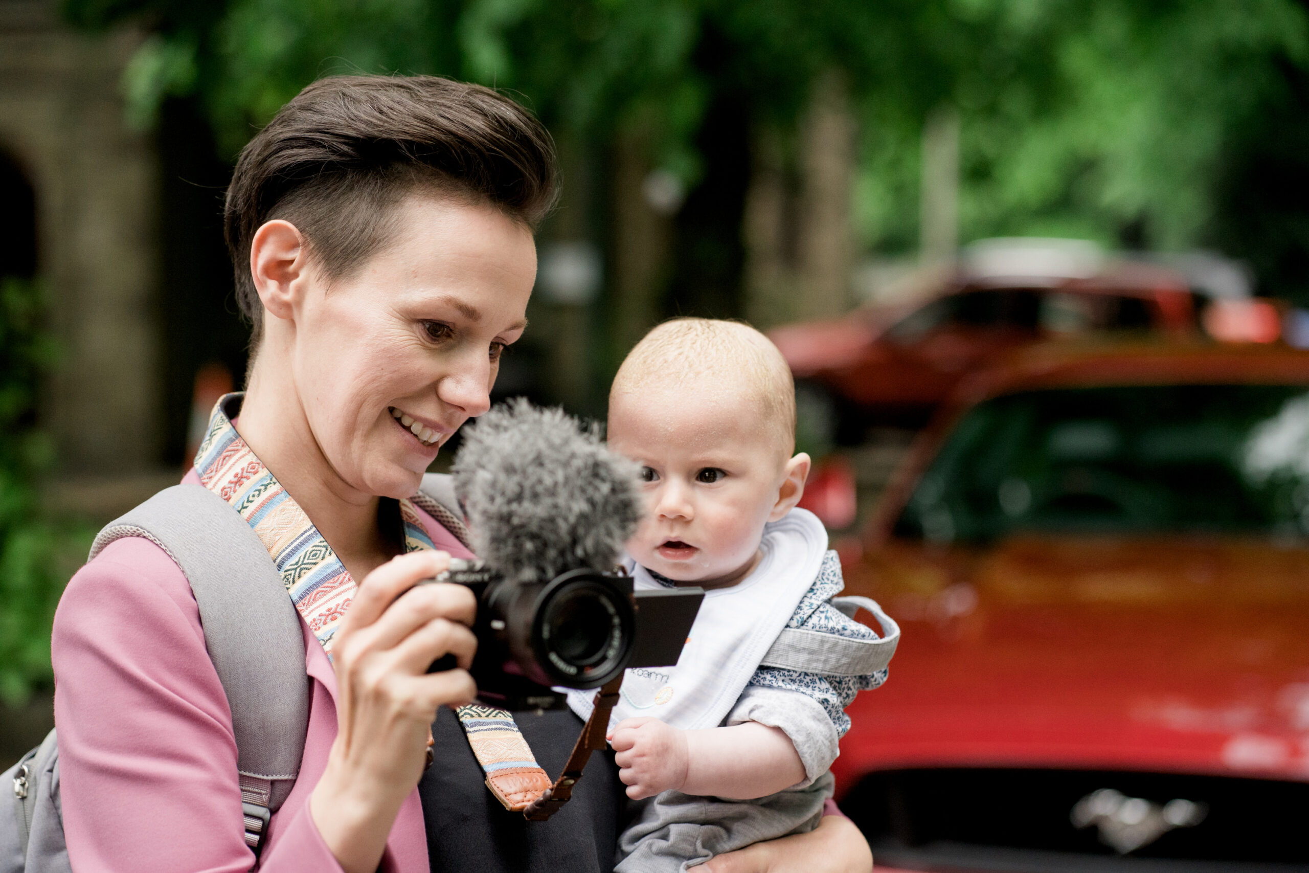 a female videographer holds a baby on her hip whilst filming a wedding in Lancashire