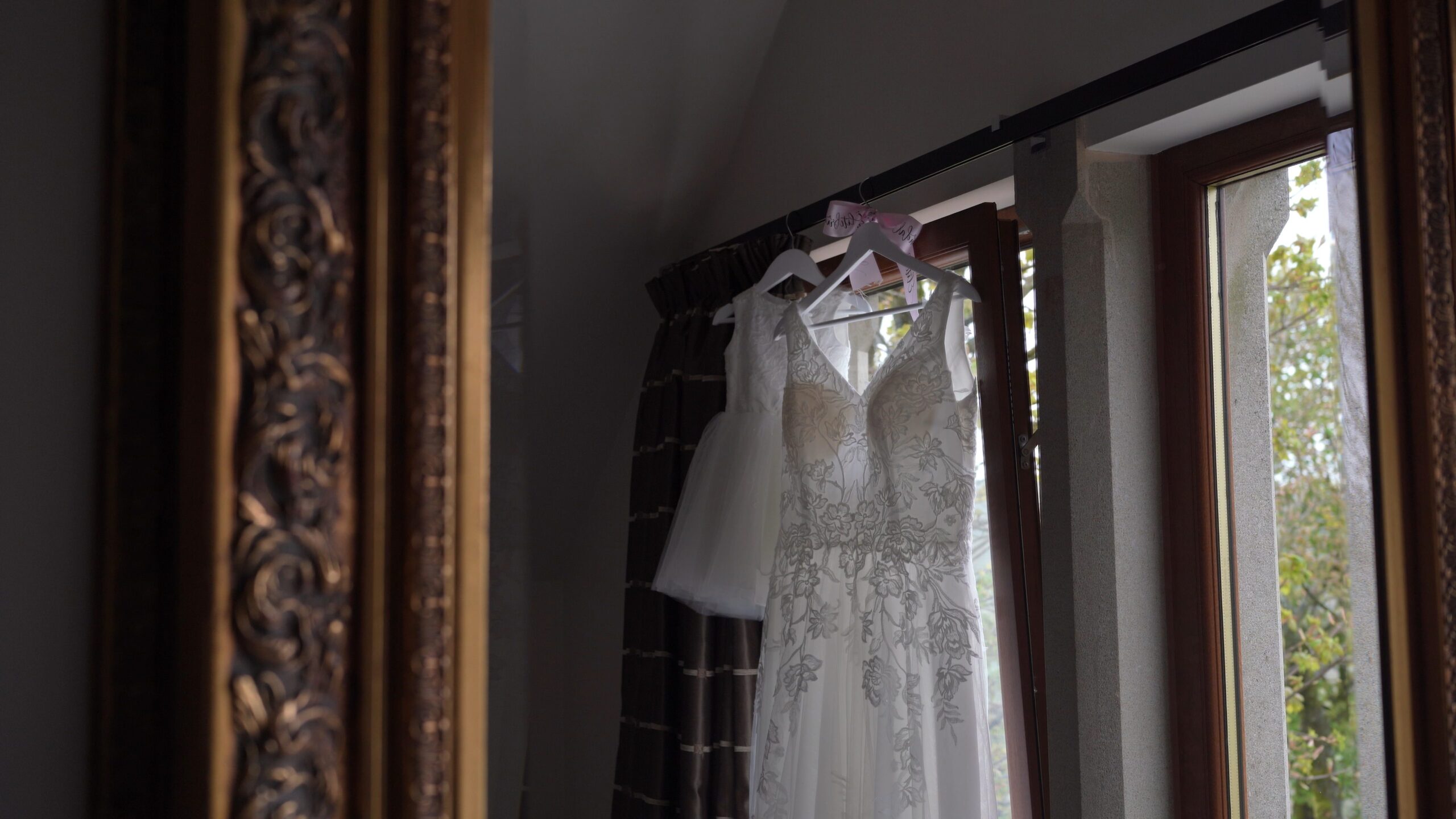 a wedding dress and flower girl dress hangs in a room at The Saddleworth Hotel Lancashire