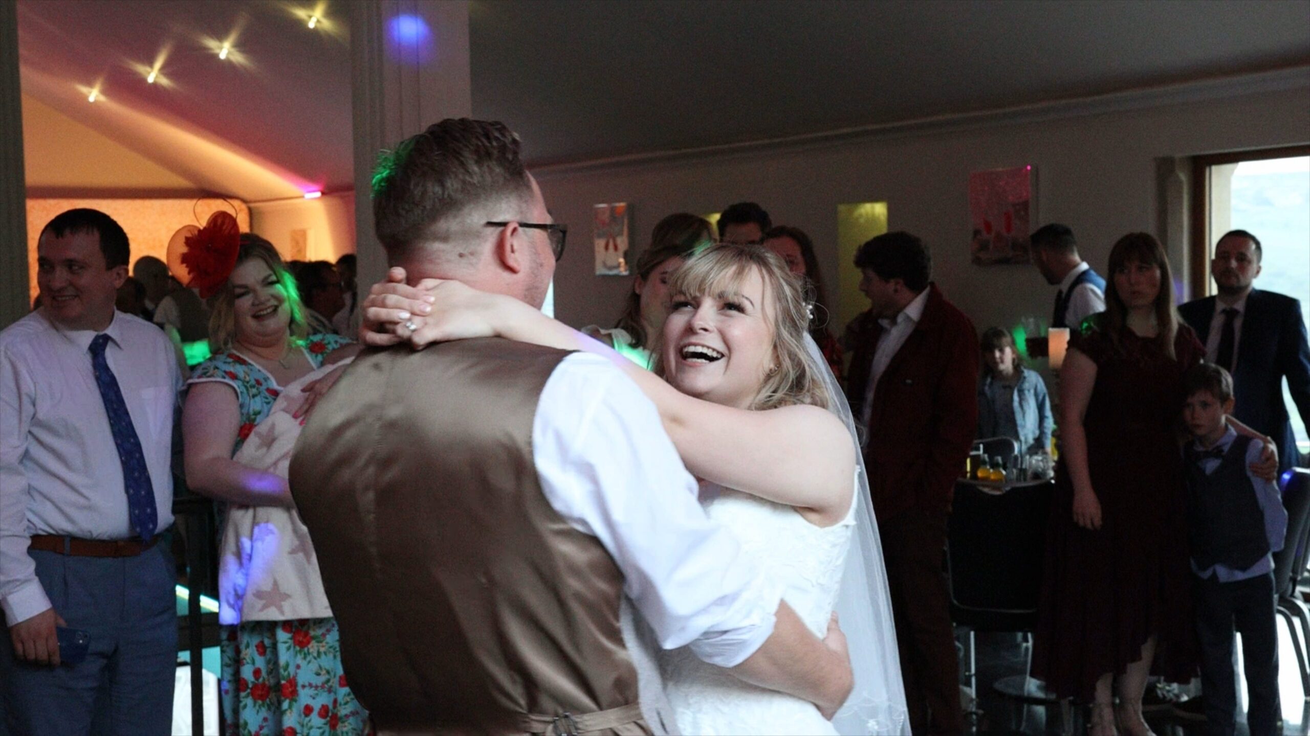 a bride and groom smile and laugh during their first dance captured by the videographer