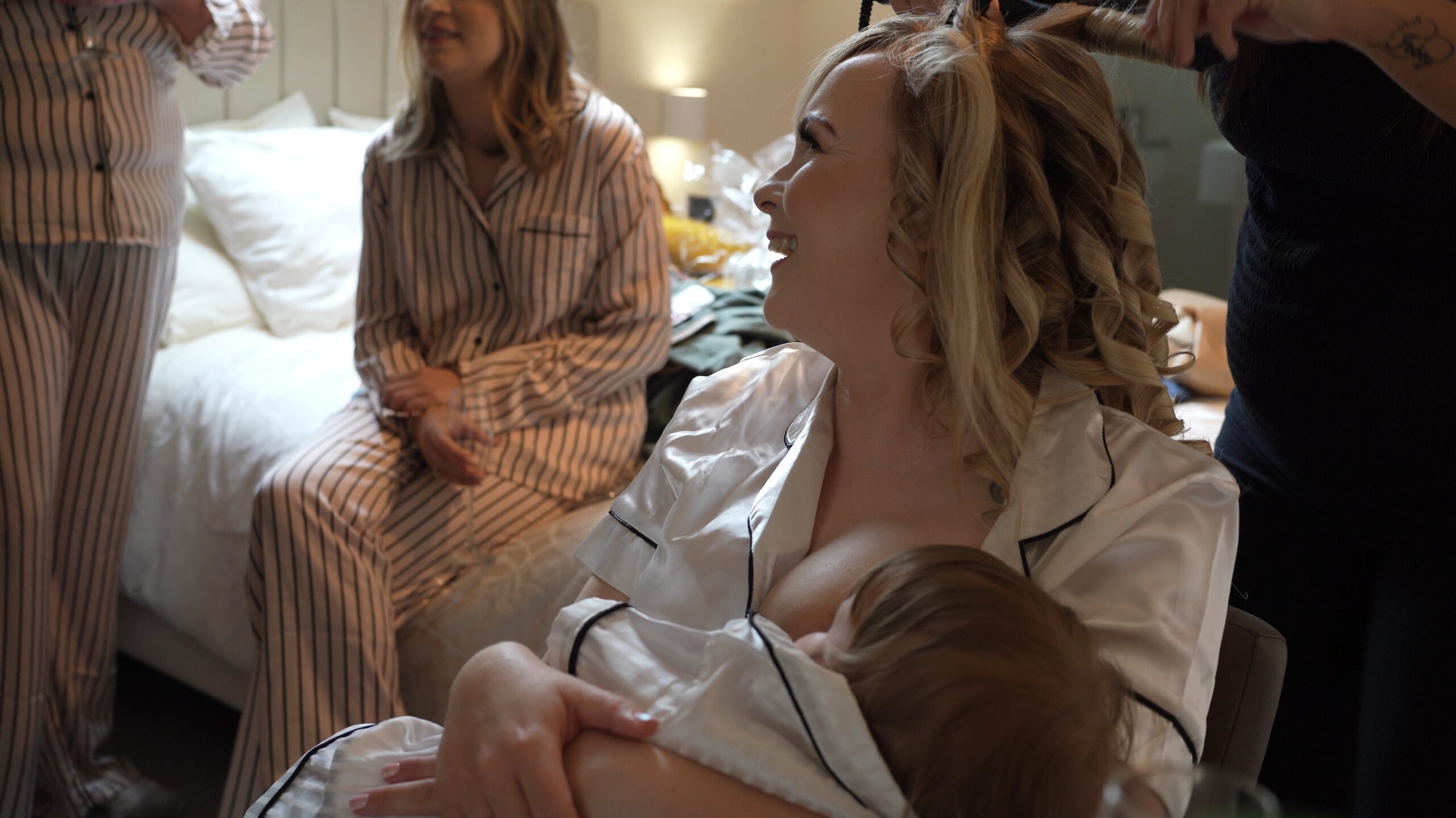 a natural video shot of a bride laughing whilst breastfeeding her baby