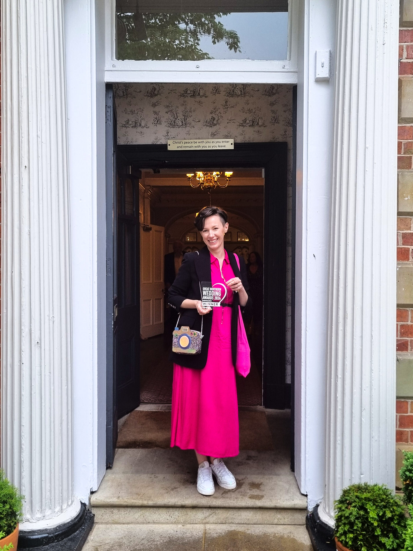 female wedding videographer standing holding her best wedding videographer award