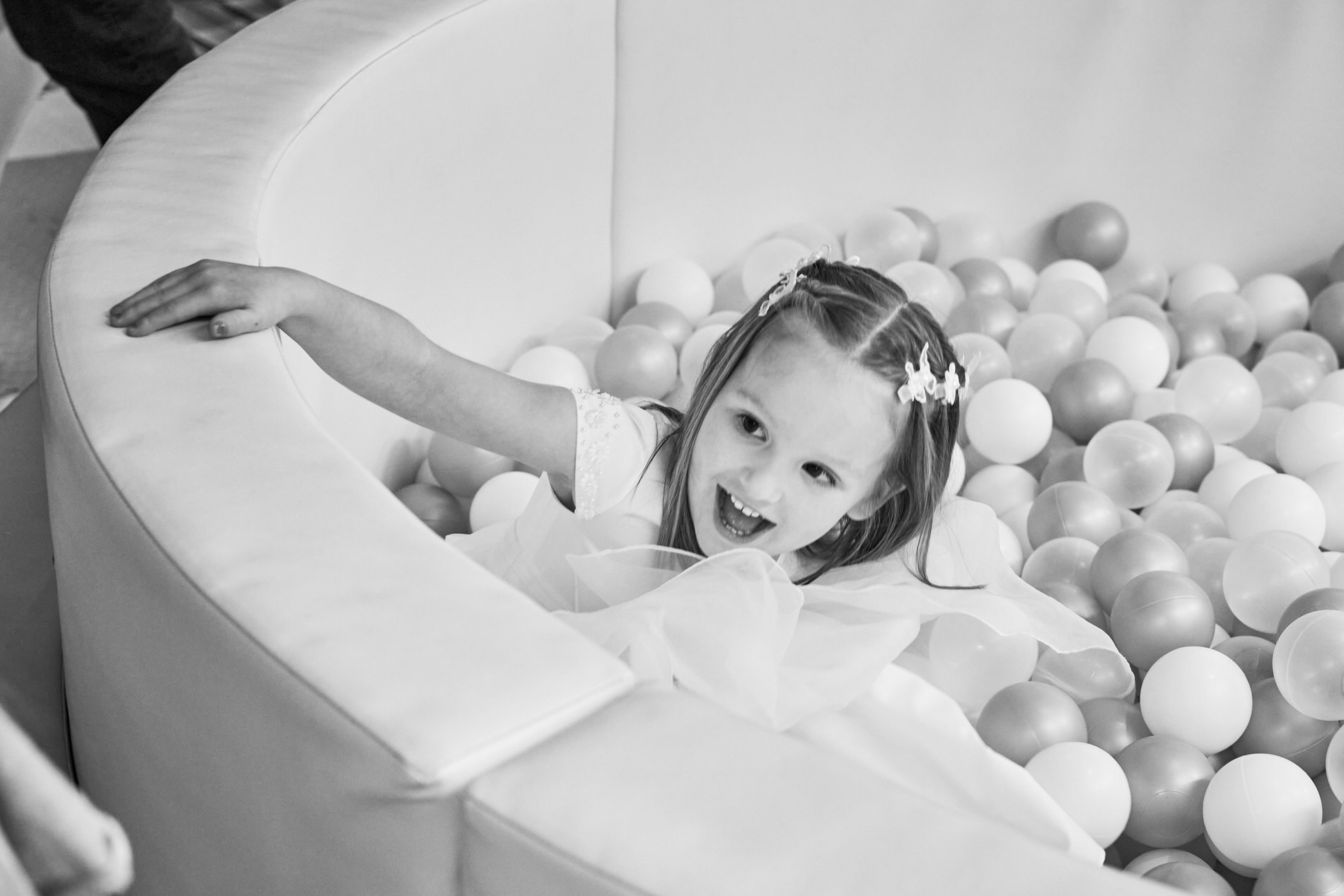 a little girl laughs as she climbs out the ball pit