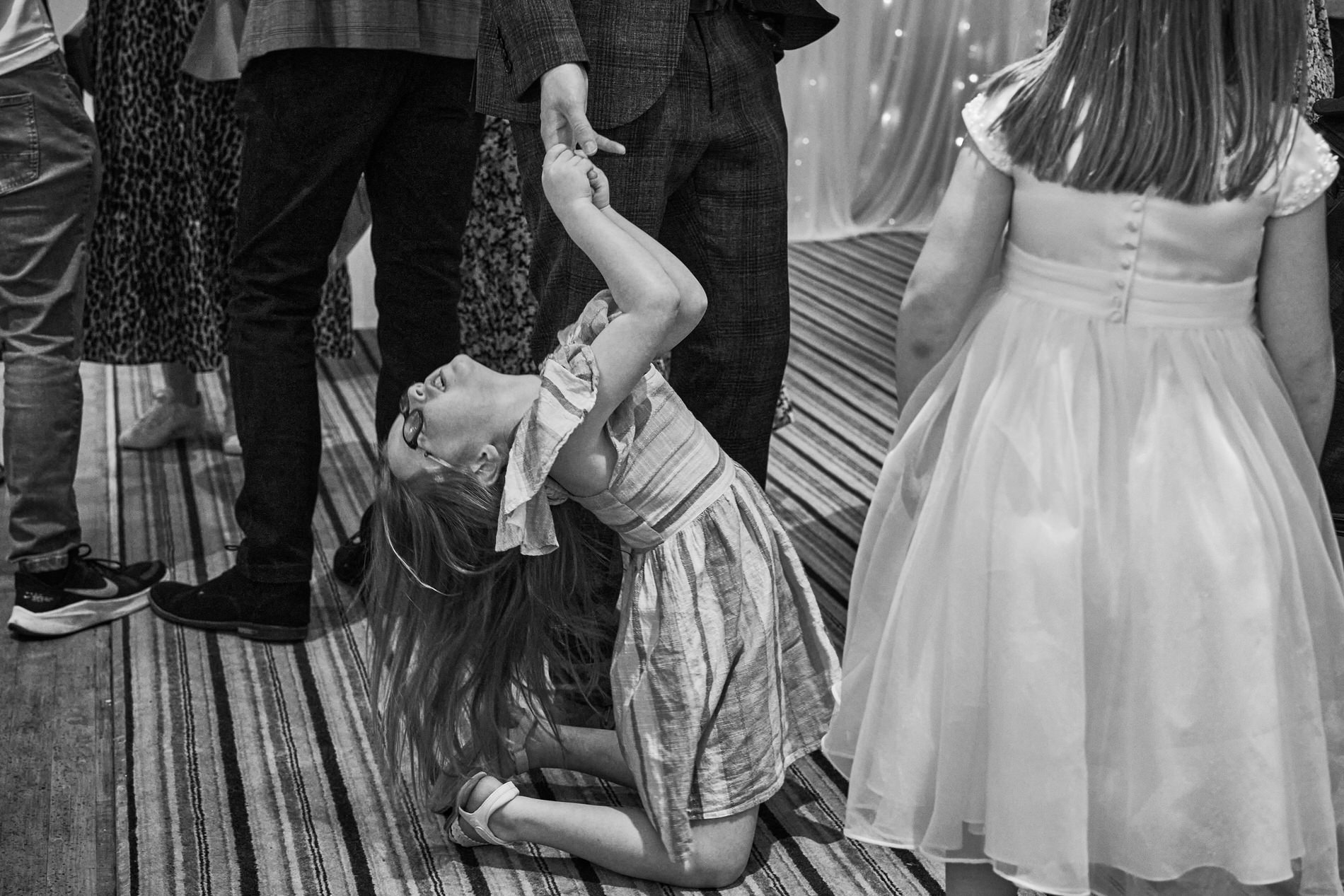 a young girl hangs off her dads arm in protest