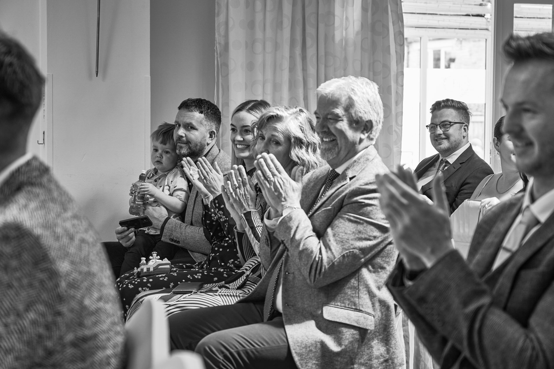 a candid photo of guests smiling and clapping during ceremony