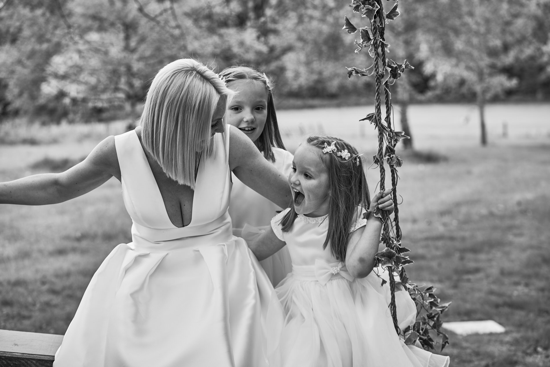 a more natural photo of the family on the swing in the gardens of Holland Hall