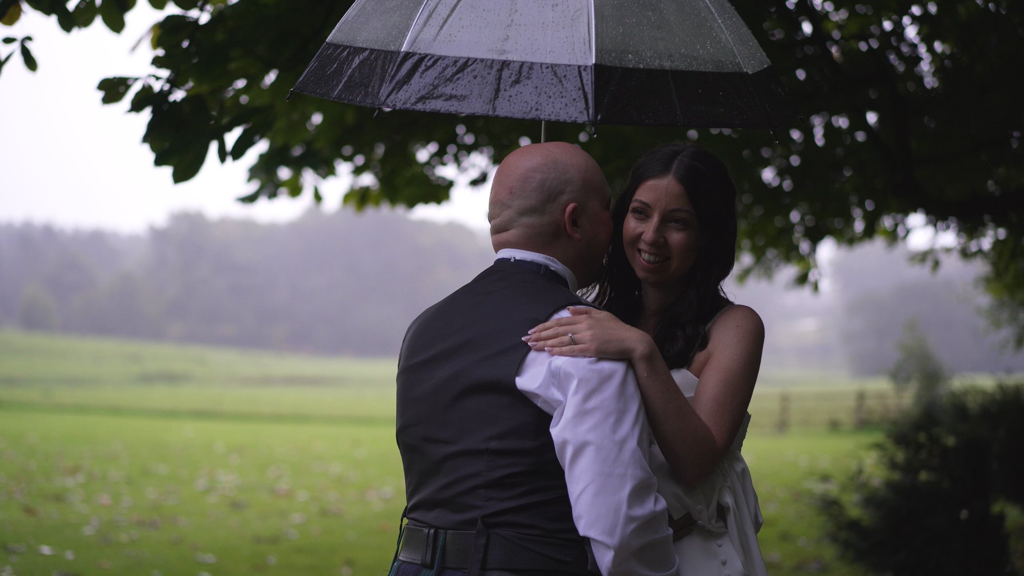 videographer captures the couple having a cuddle under an umbrella in the pouring rain outside Browsholme Hall