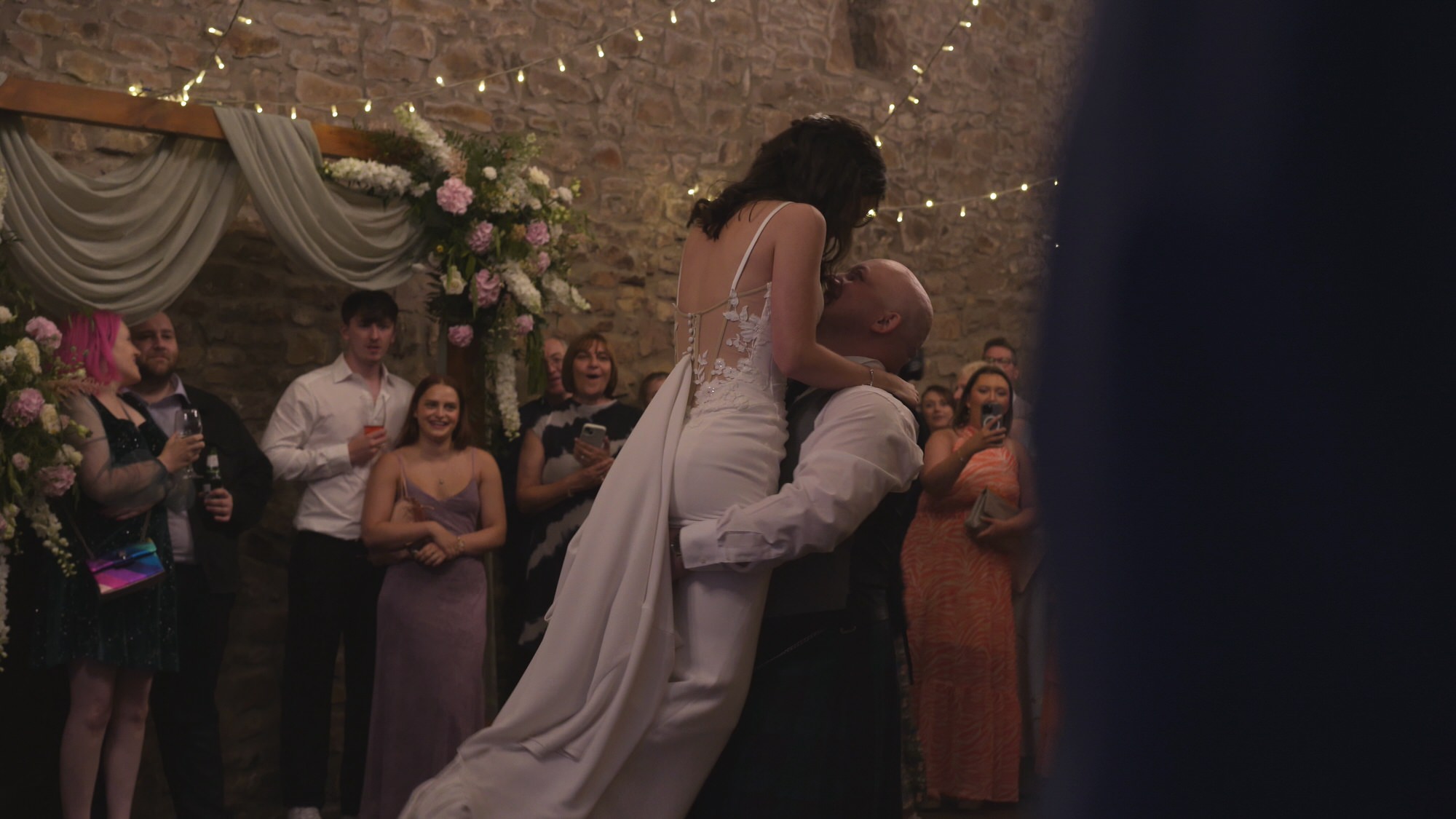 guests cheer as the groom lifts up the bride during their first dance