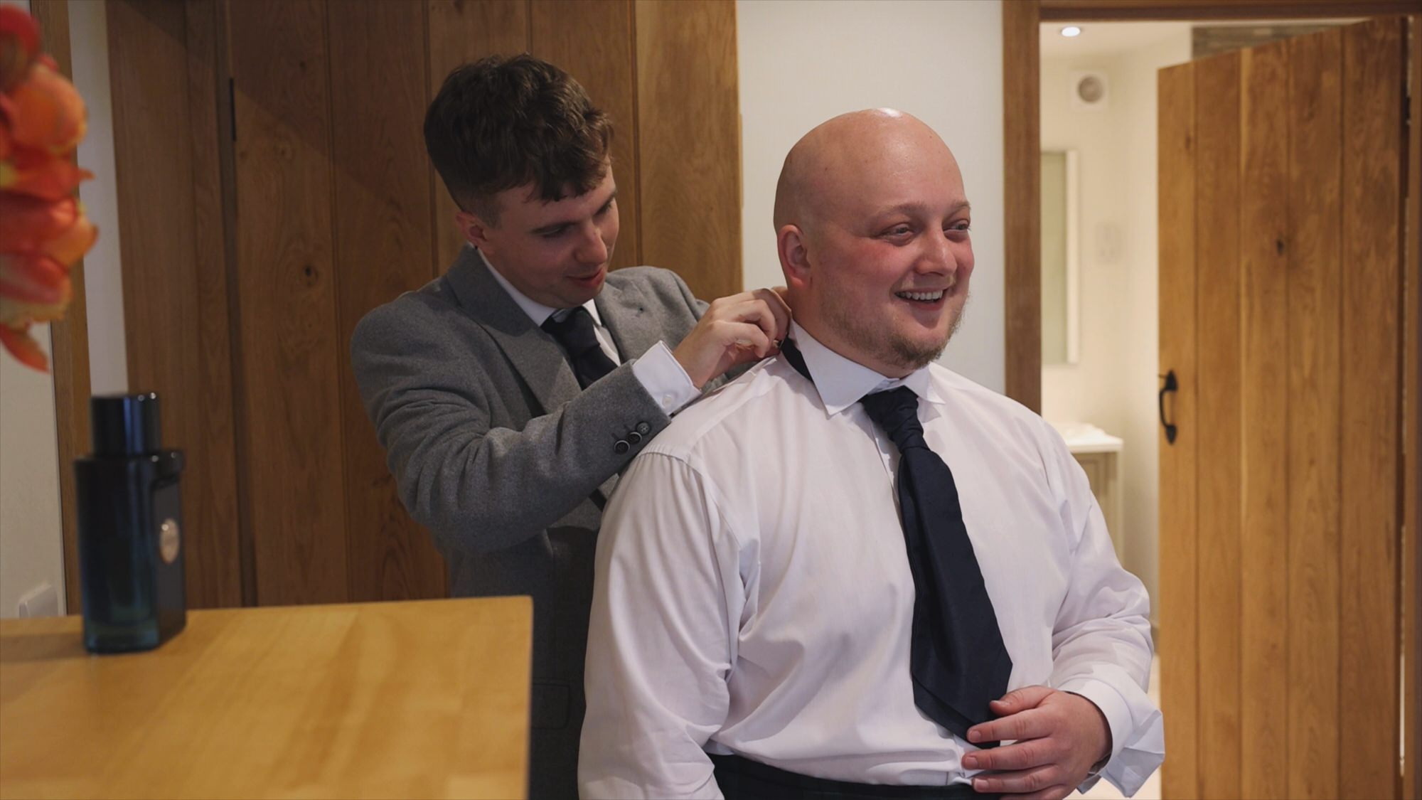 an usher helps the groom with his tie