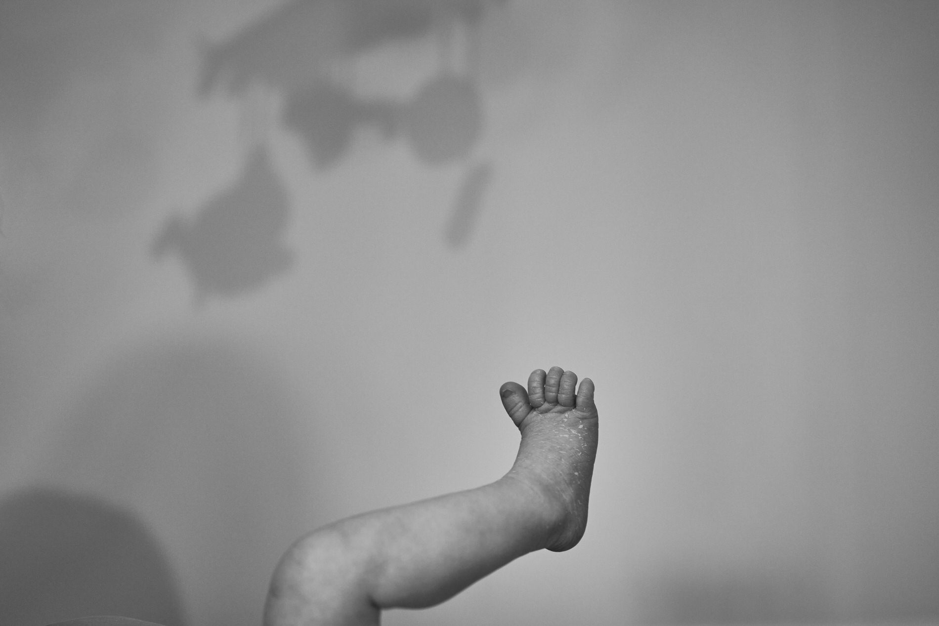black and white photo of a newborn babys foot and nursery shadows
