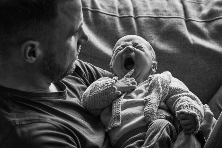 a black and white photo of a baby yawning during family photoshoot in Burscough