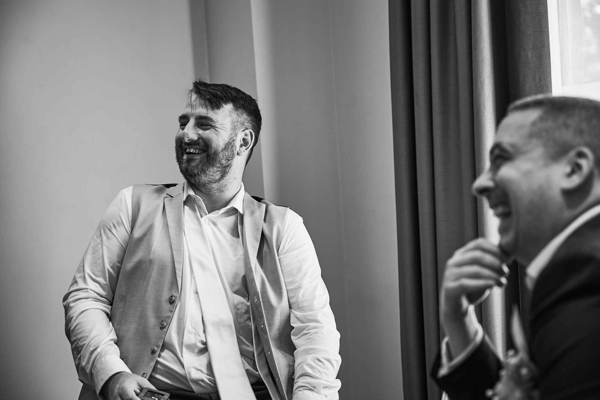 a candid photo of a groom laughing with his best man