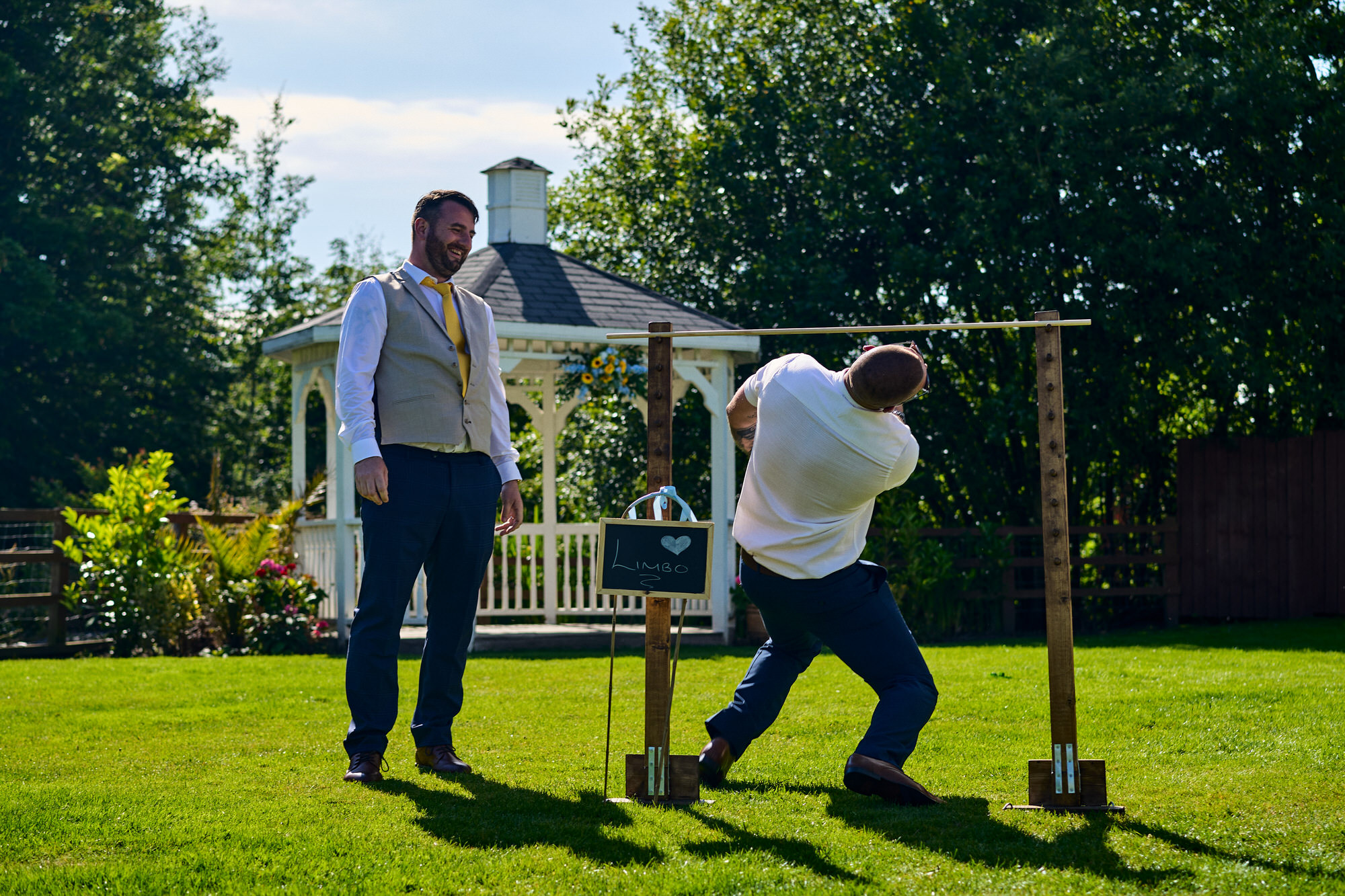 a groom and guests compete in a game of limbo