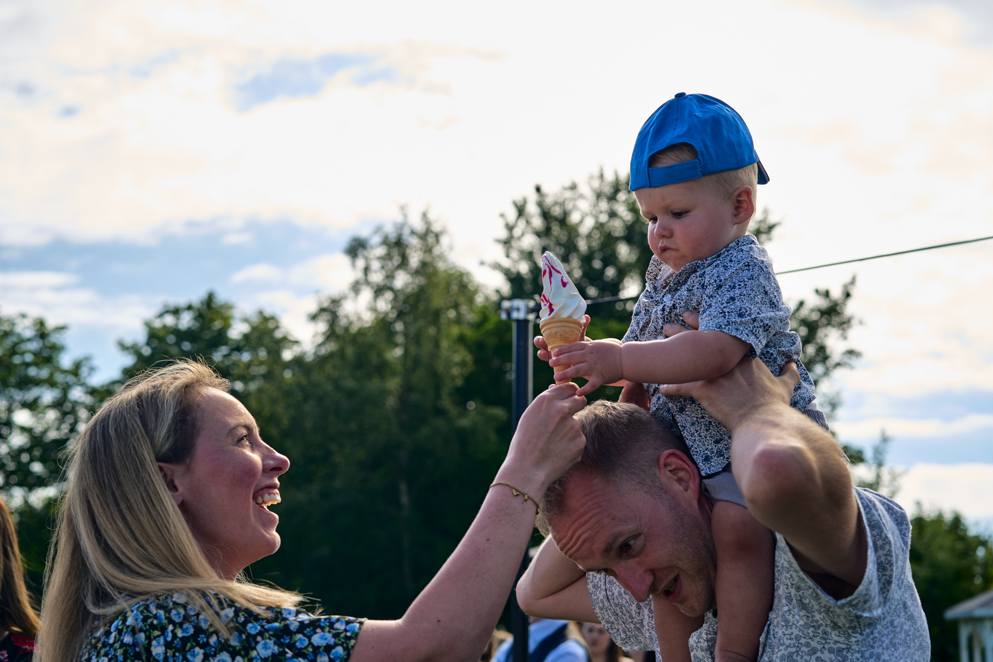 a mum gives a toddler an ice cream at a wedding