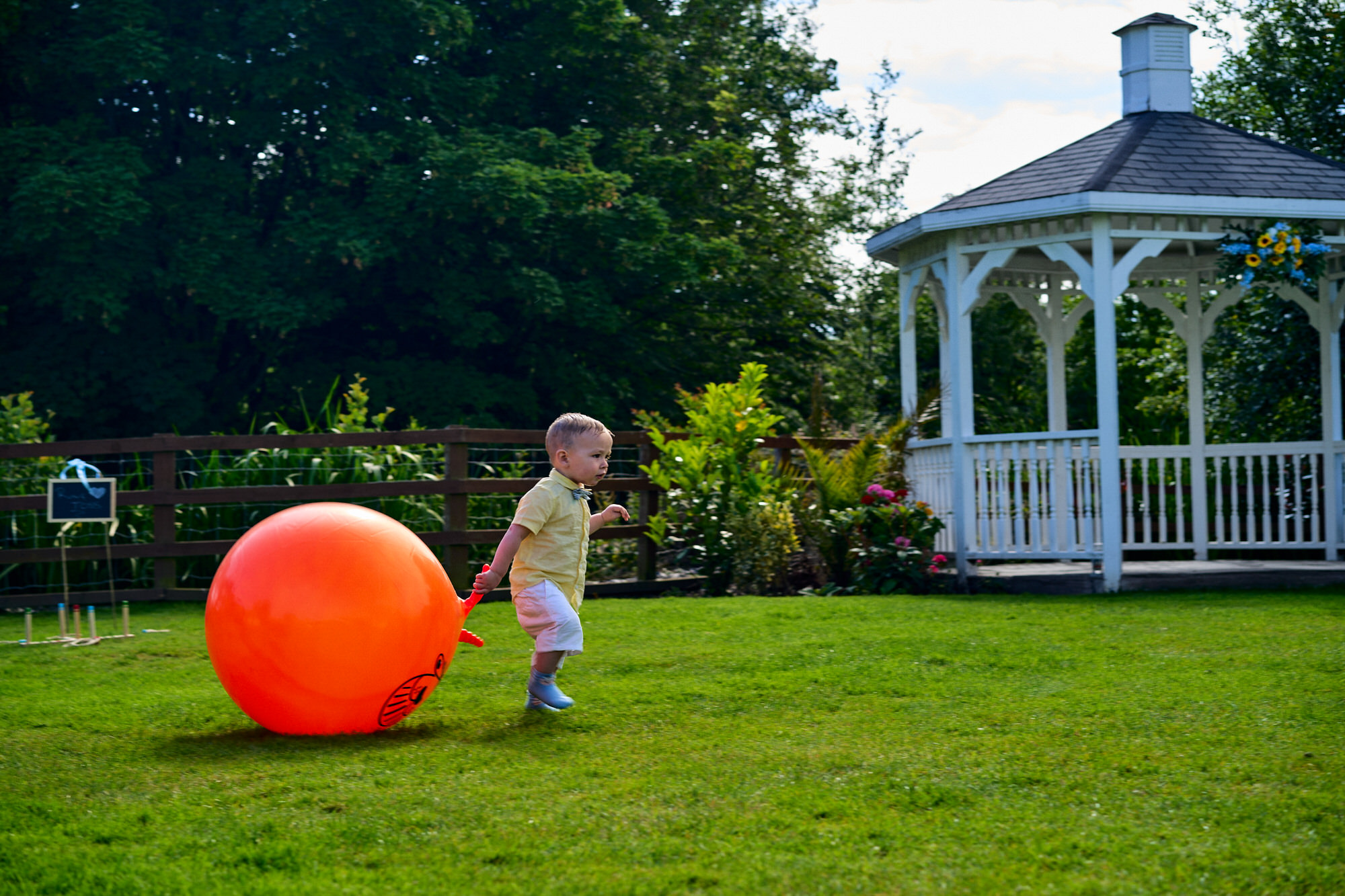 a fun photo of a small child dragging a large space hopper at a wedding