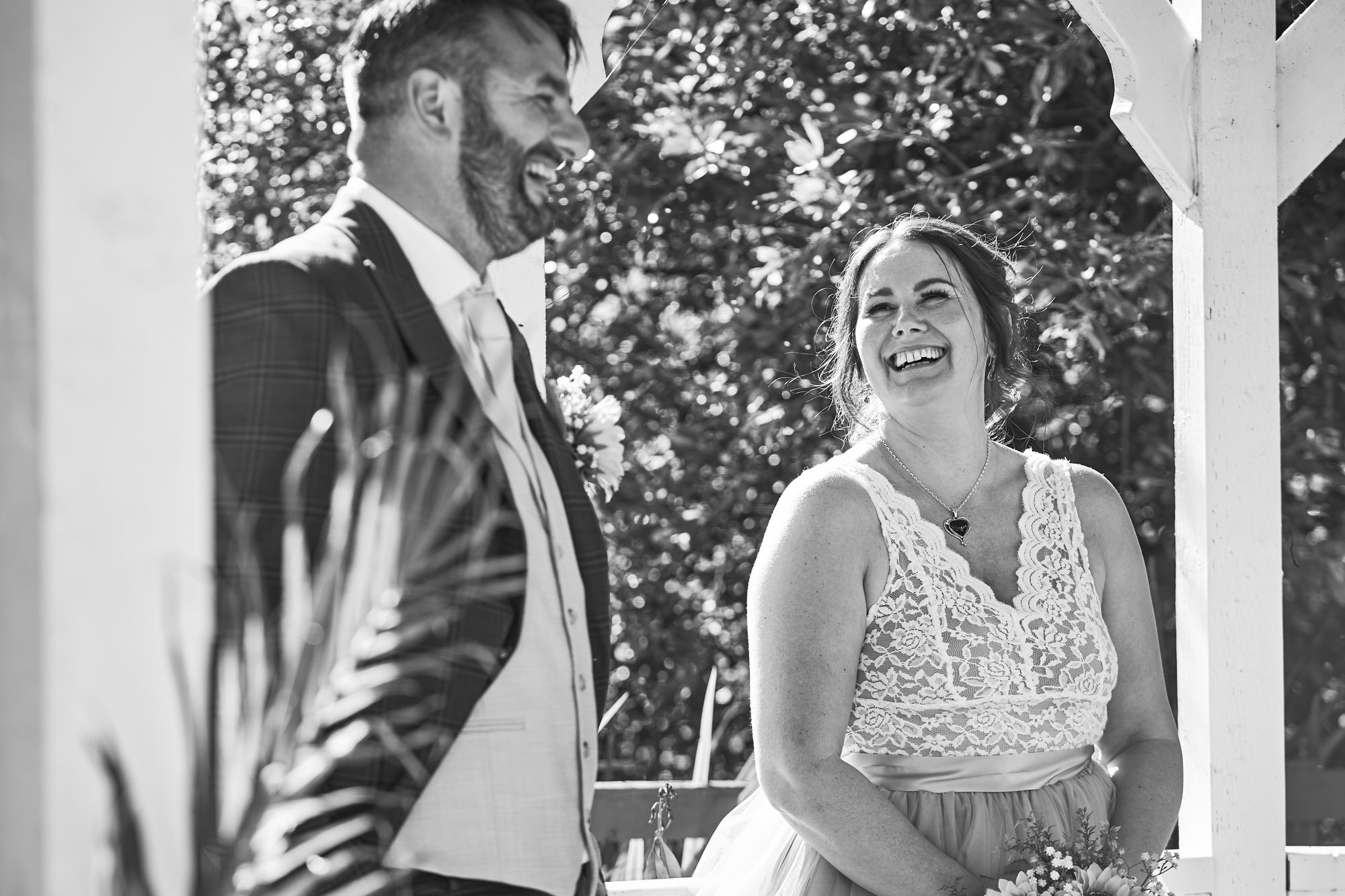 a couple laugh together for a candid photo on their wedding day