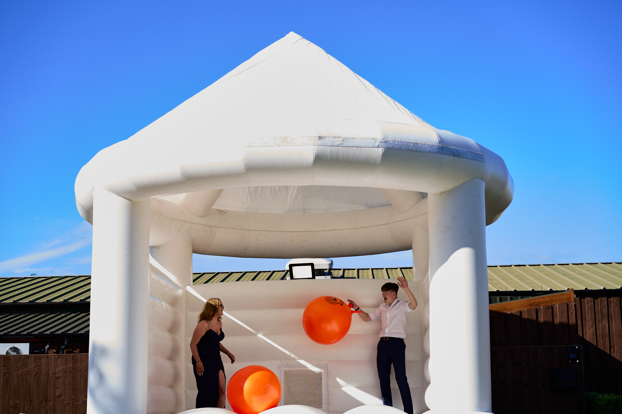 guests jump on a white wedding bouncy castle