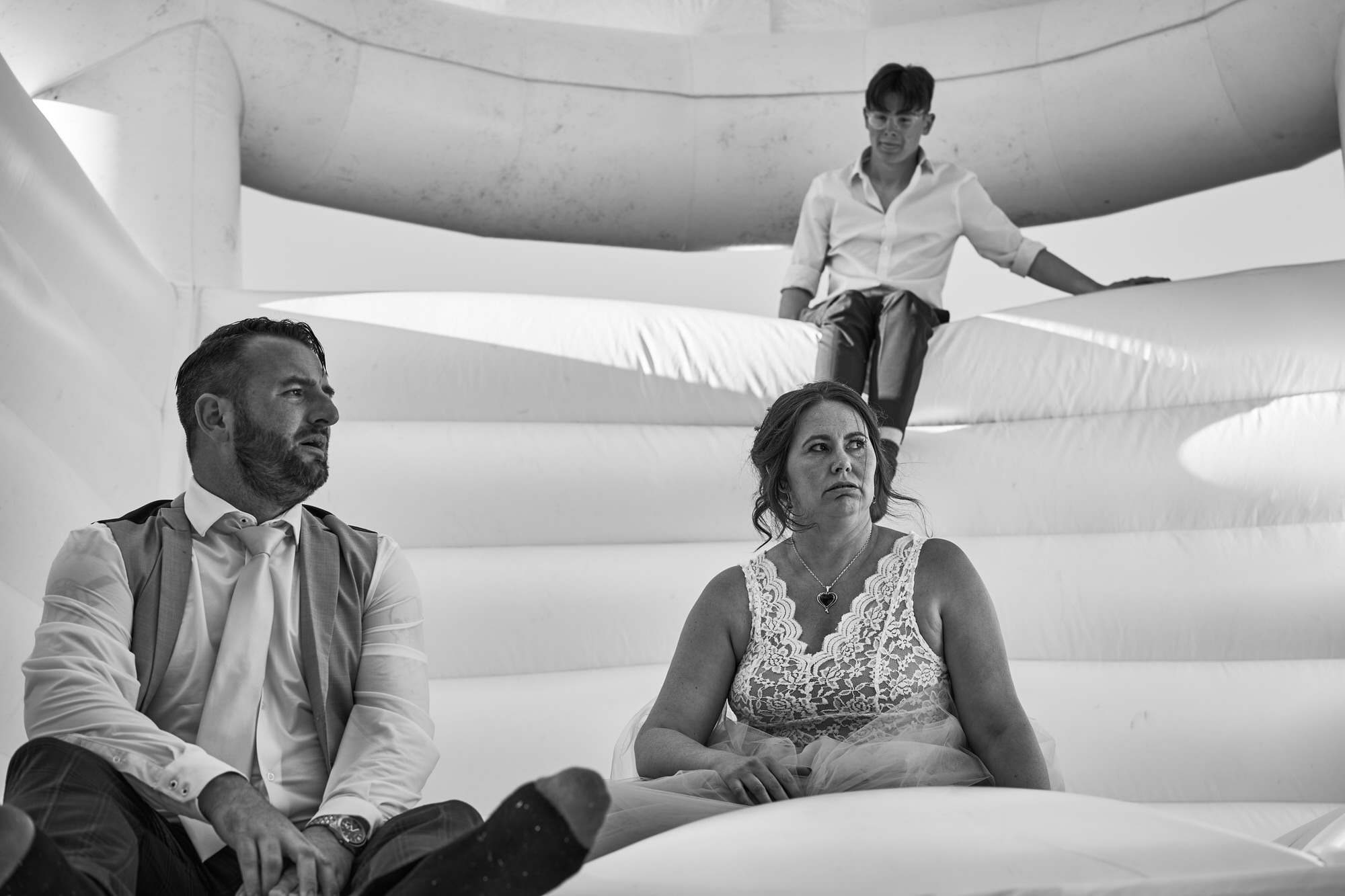 a couple look exhausted after jumping on a wedding bouncy castle