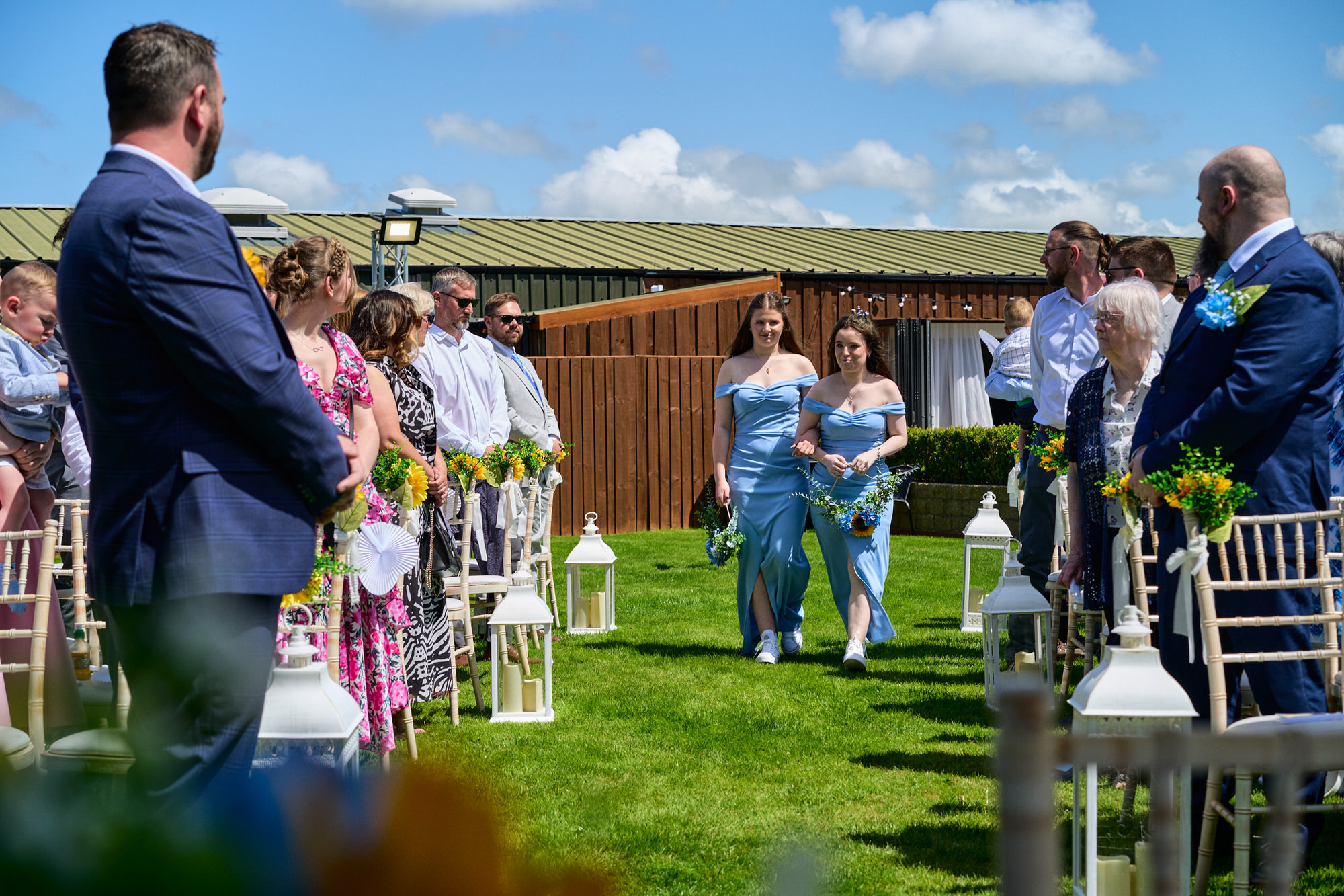 two bridesmaids walk down the outdoor aisle at The Aviary Ormskirk