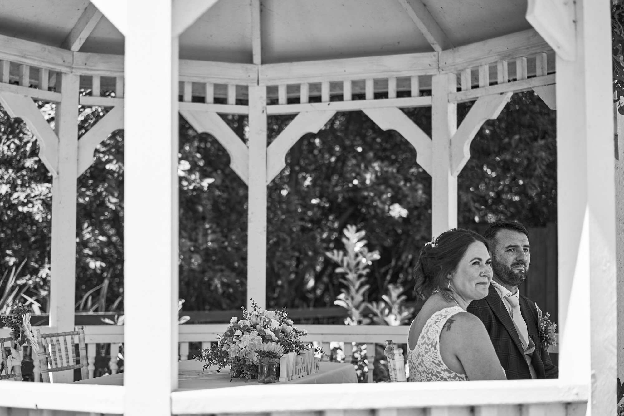 a couple sit in the shade during their outdoor wedding ceremony at The Aviary Ormskirk