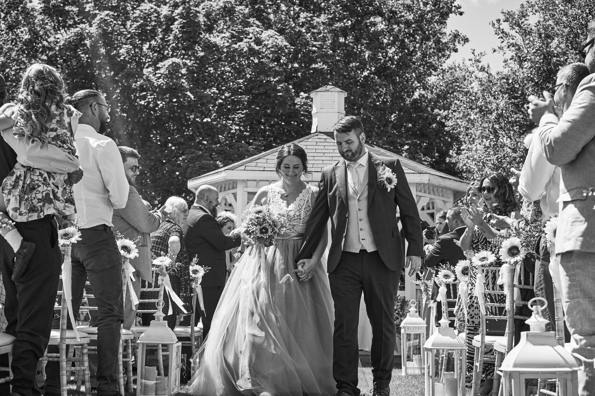 a happy couple walk down the outside ceremony aisle at The Aviary Ormskirk