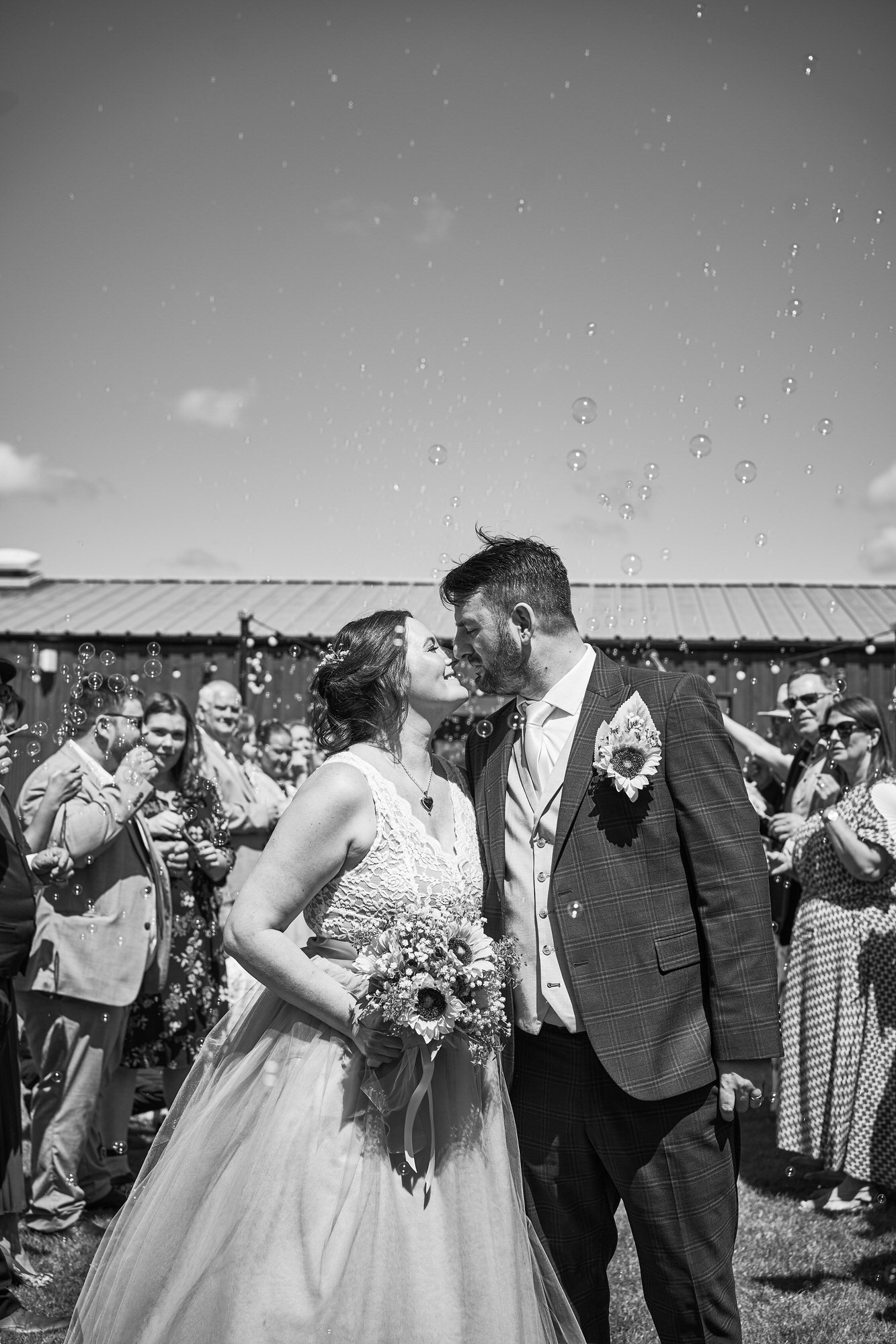 a black and white photo of a couple kissing during bubbles at wedding