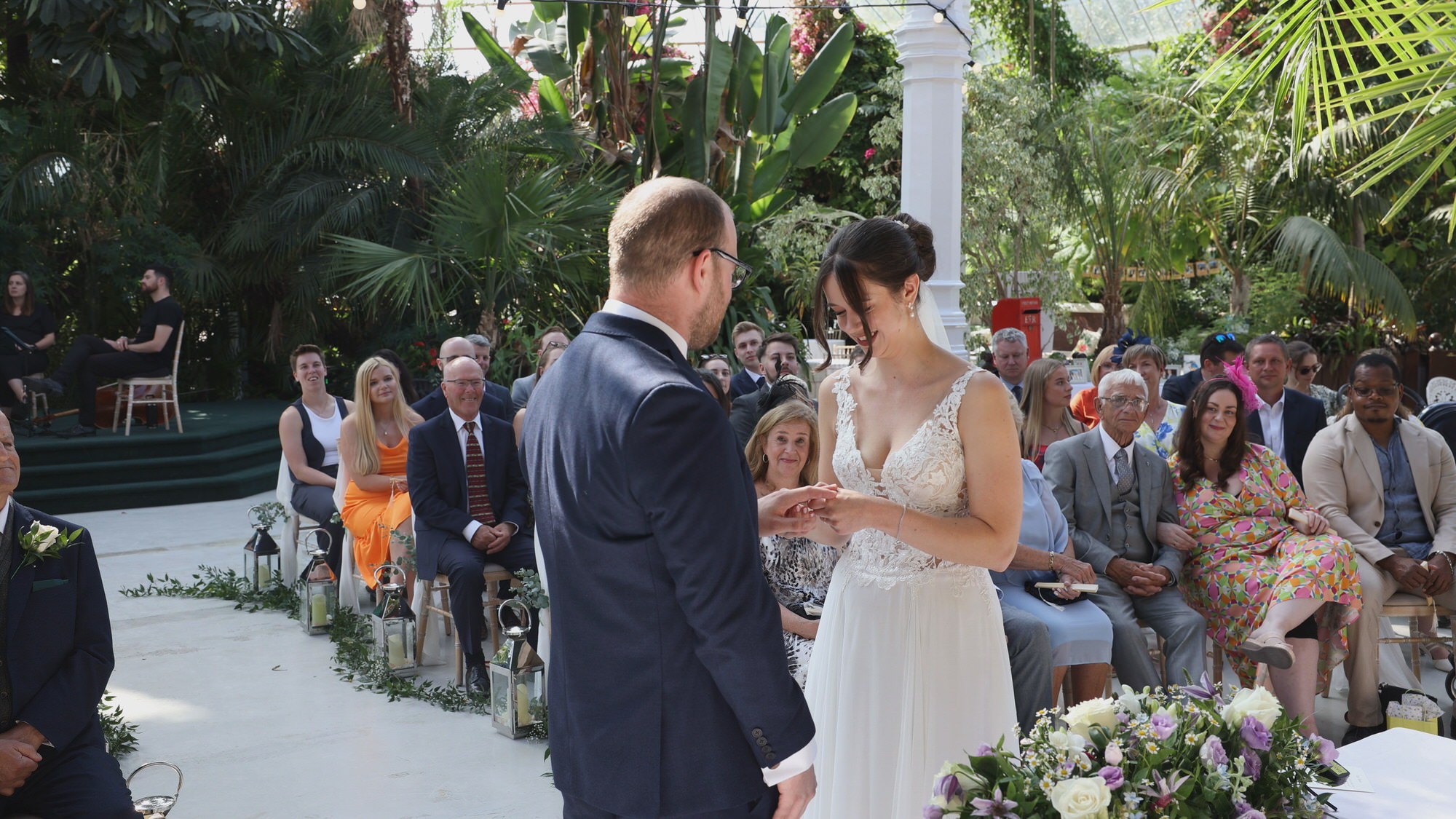 a bride puts on her grooms ring at Sefton Park Palm House wedding ceremony