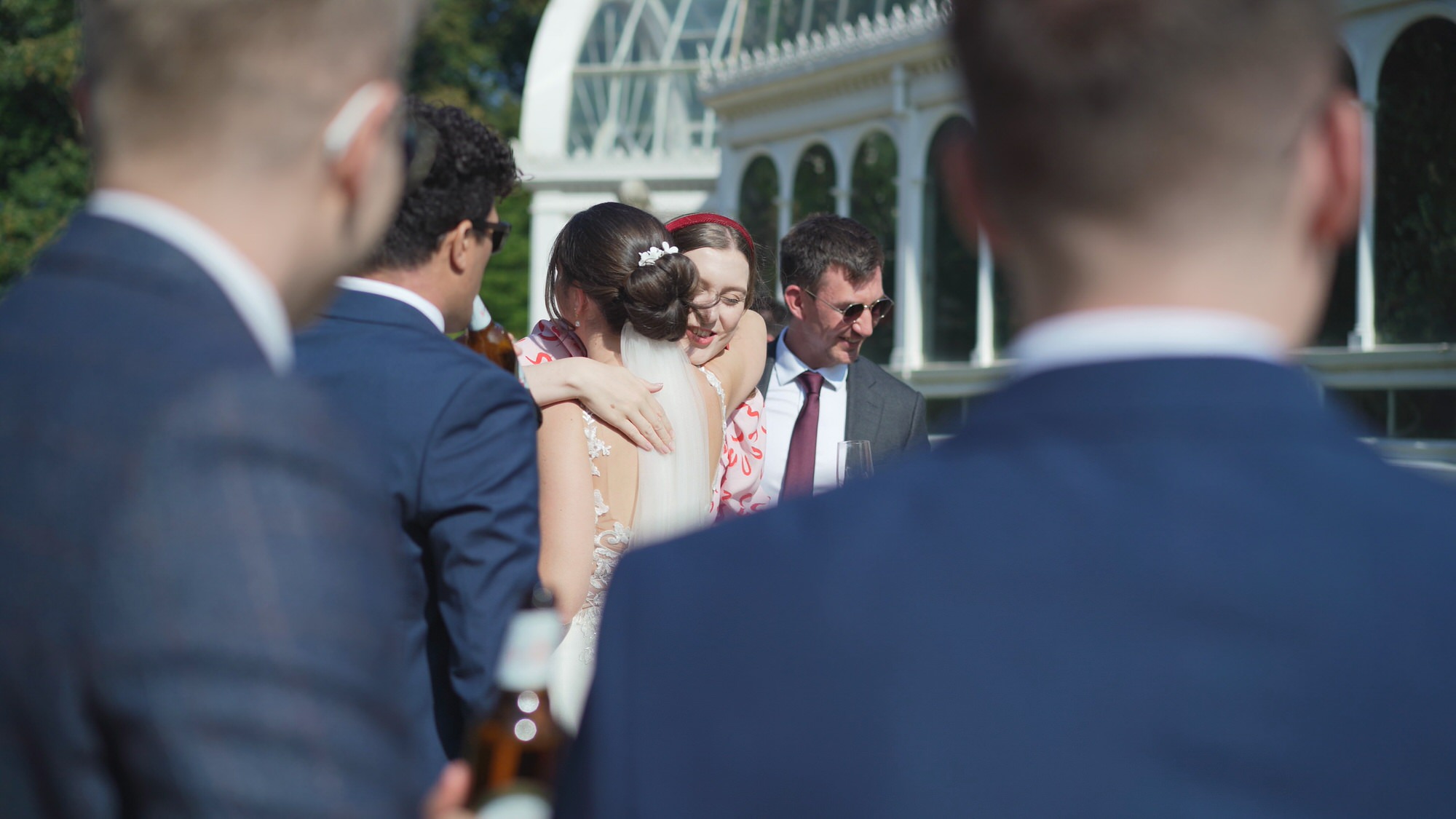 a candid video still of guests hugging bride during Sefton Park Palm House wedding