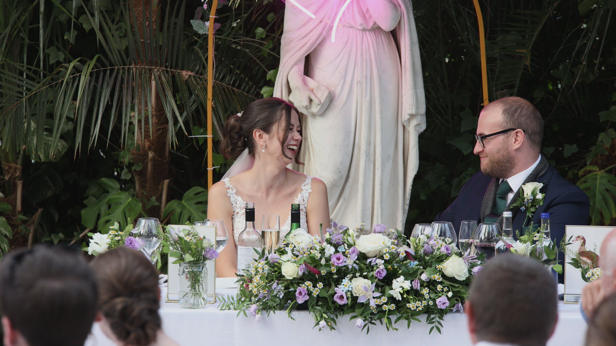 the couple laugh during a mother of the bride speech at Sefton Park Palm House Liverpool