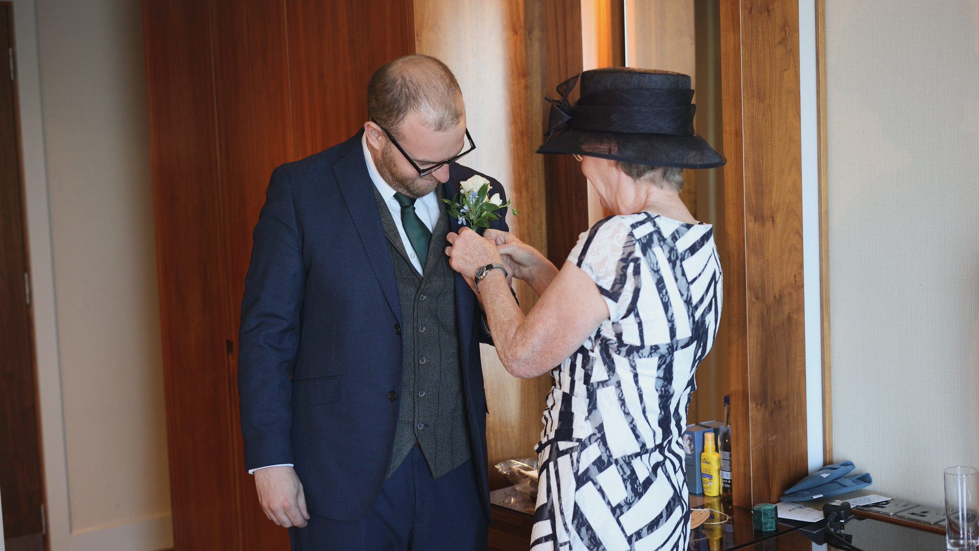 grooms mum helps adjust a button hole on a wedding morning