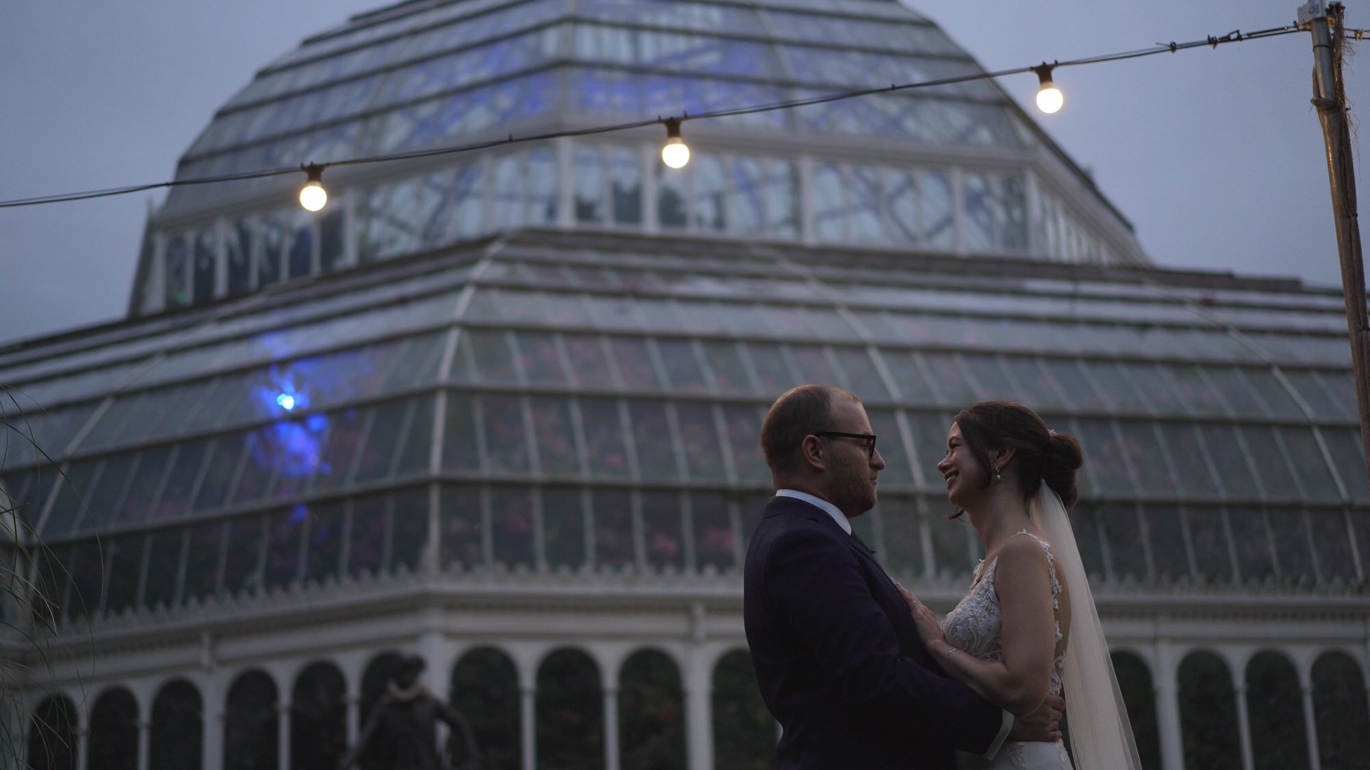 a video still of a couple at dusk under festoon lights at Sefton Park Palm House Liverpool