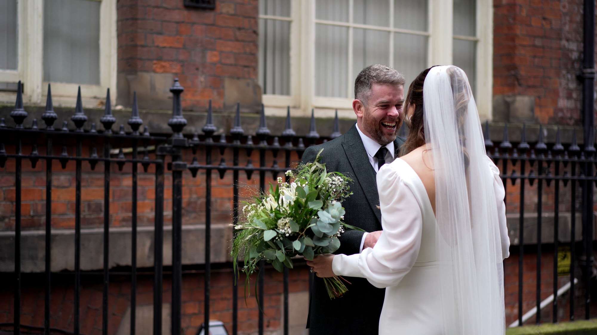 a bride and groom laugh with each other during candid moments of videography
