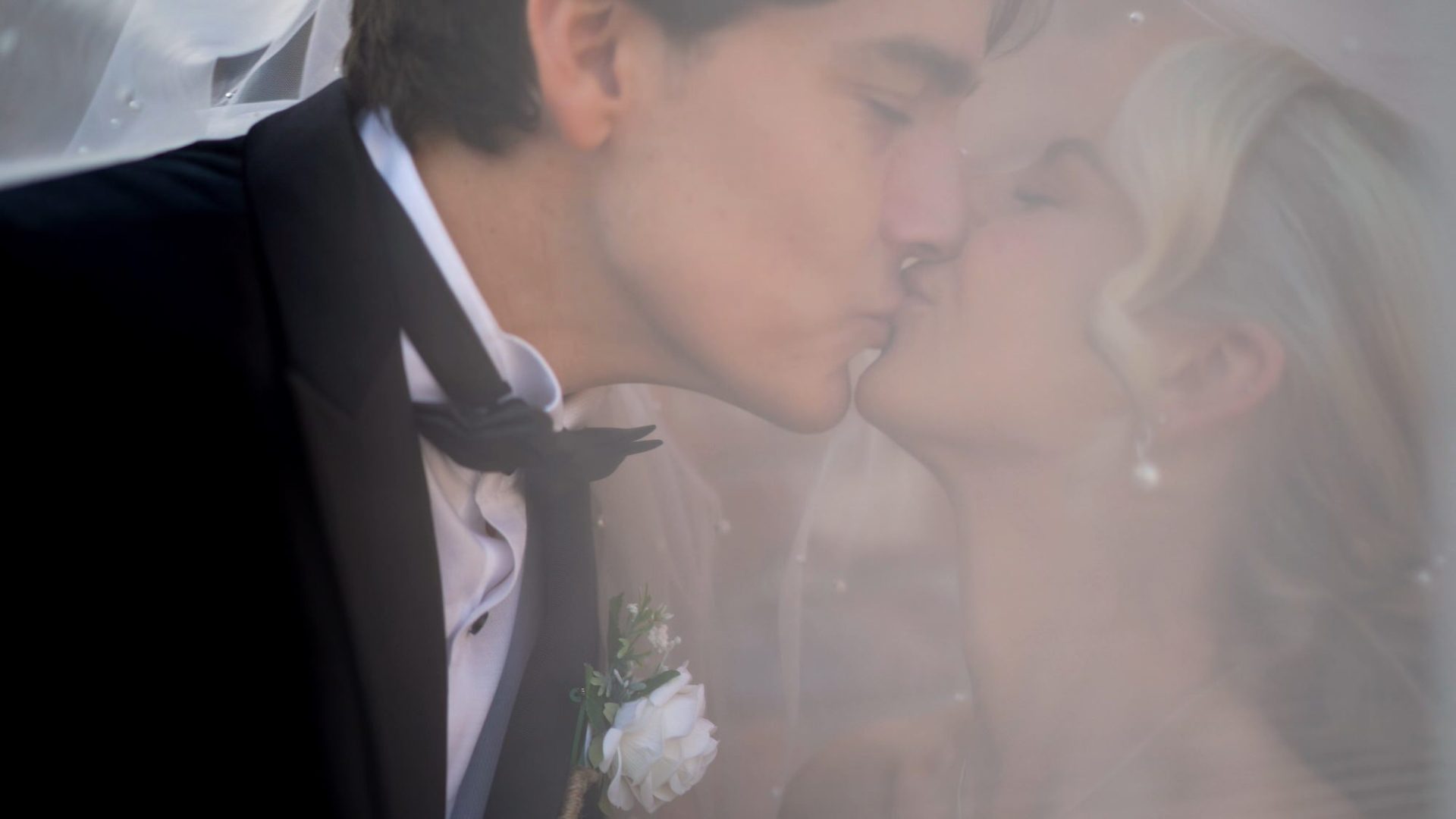 a unique video shot of a couple kissing under a veil outside Larkspur