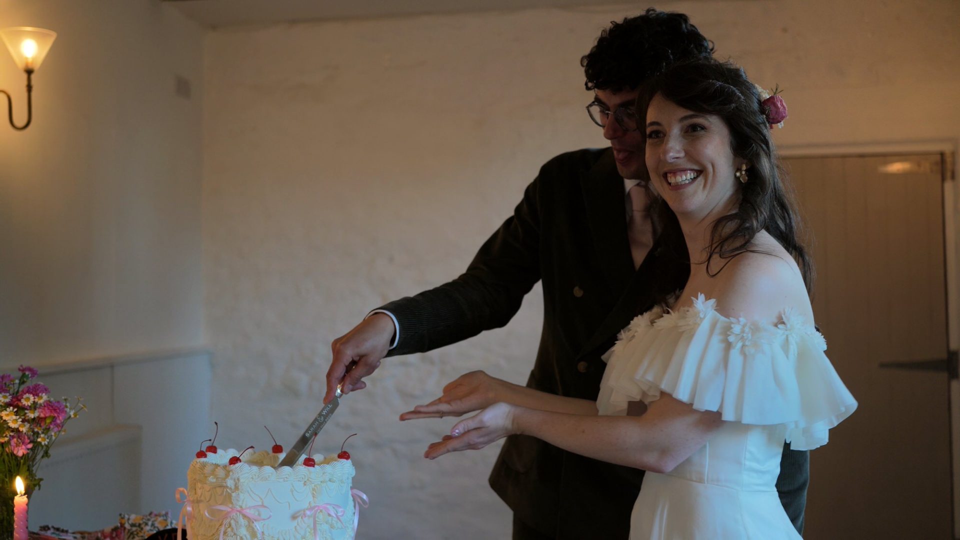 a couple pose with their vintage inspired cherry topped wedding cake