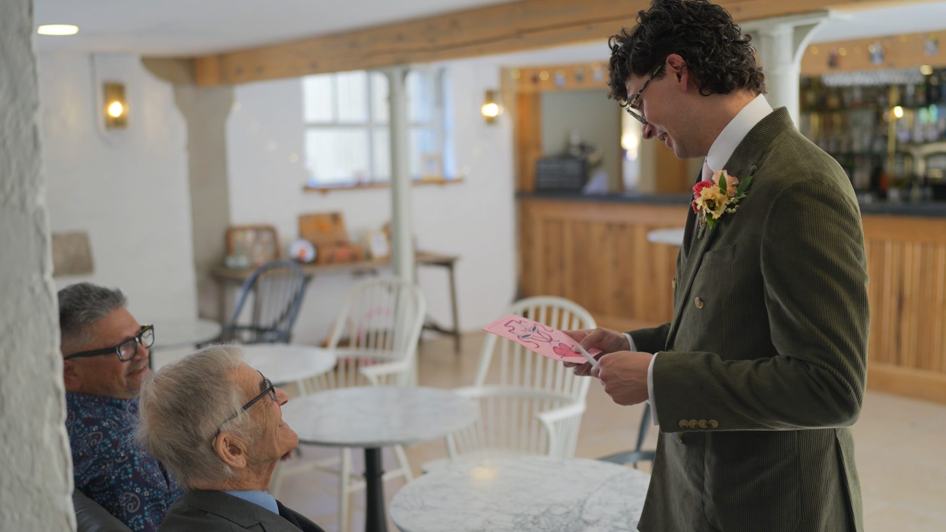 the groom smiles at a handmade card from grandad at their wedding
