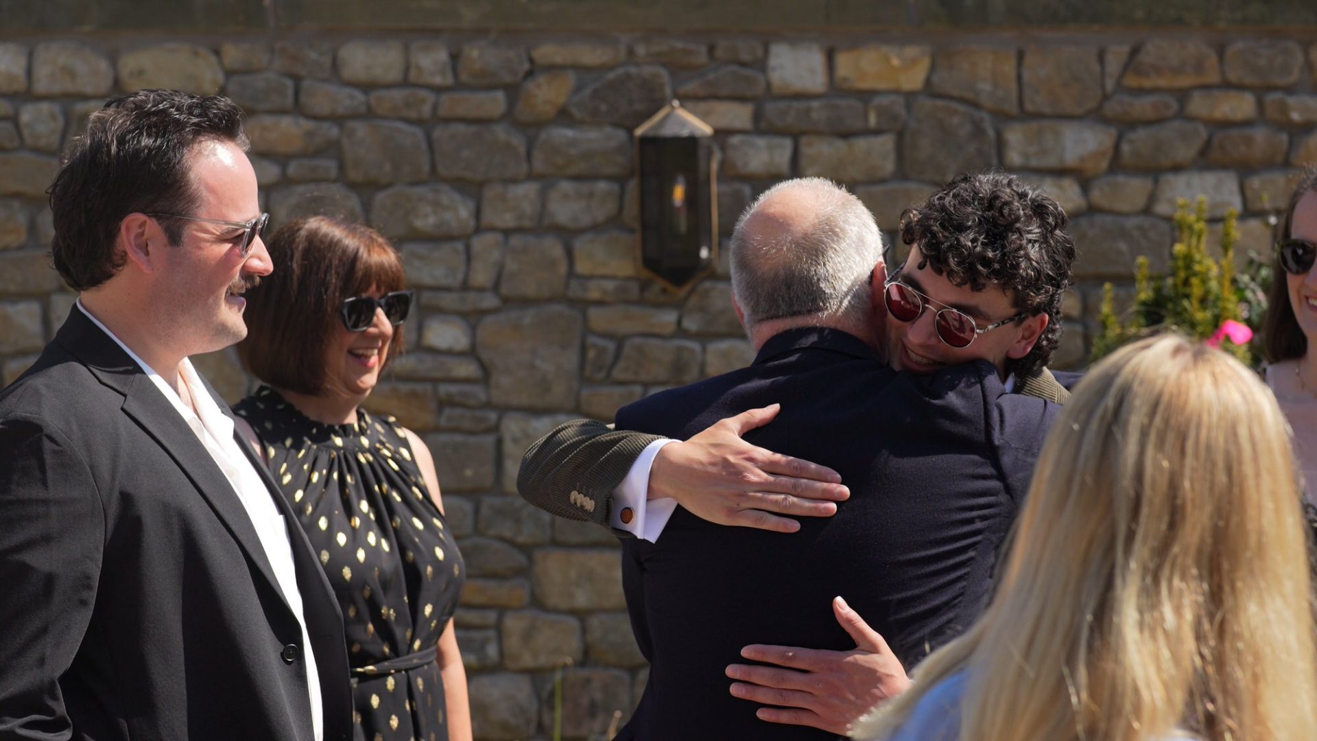 a groom hugs wedding guests outside the barn at Wyresdale Park