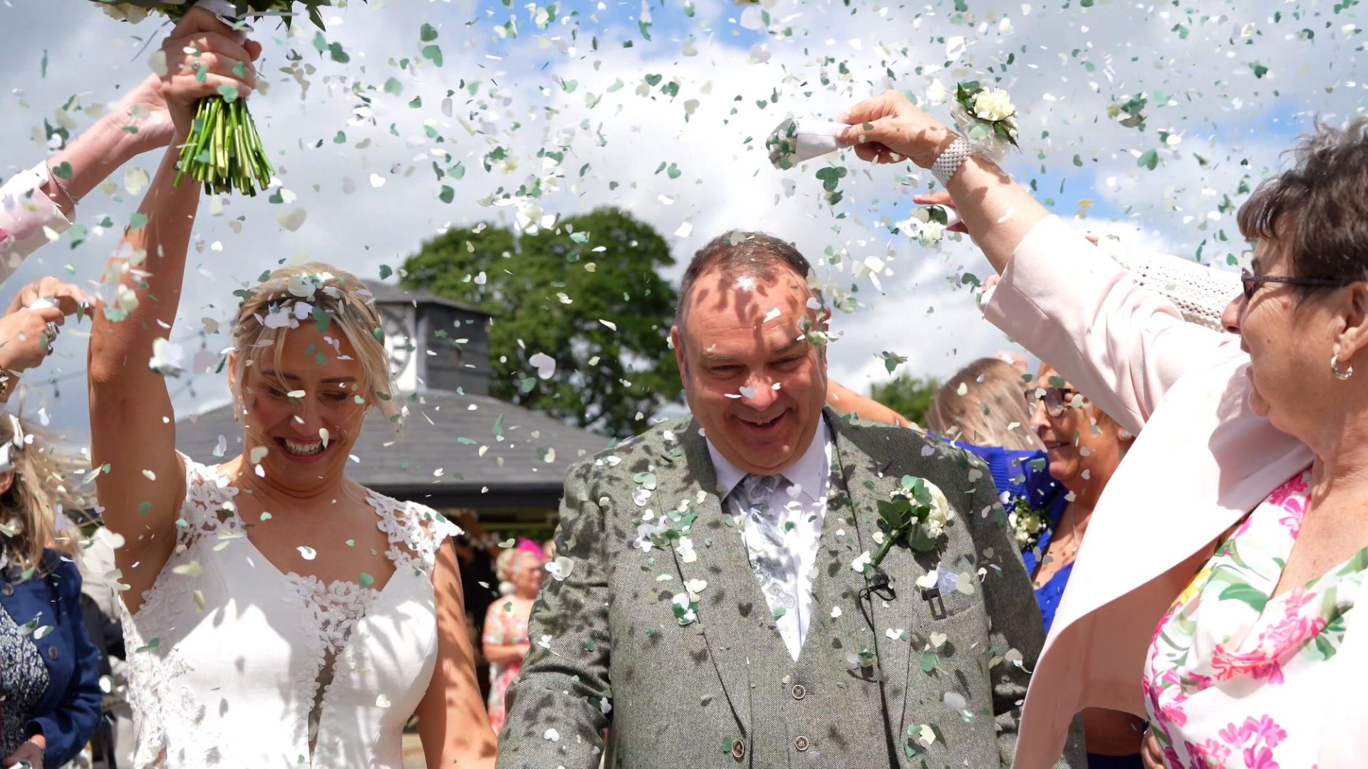 a video still of a couple showered in green and white confetti