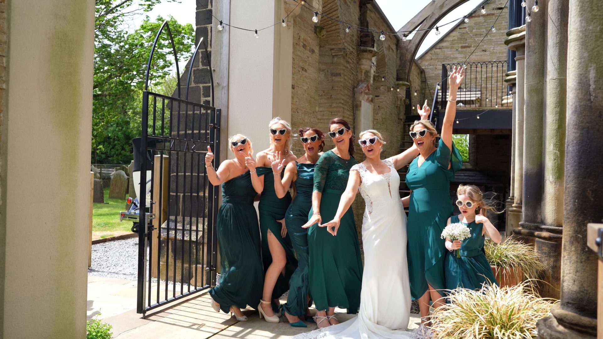 a videographer films the bridal party posing in sunglasses