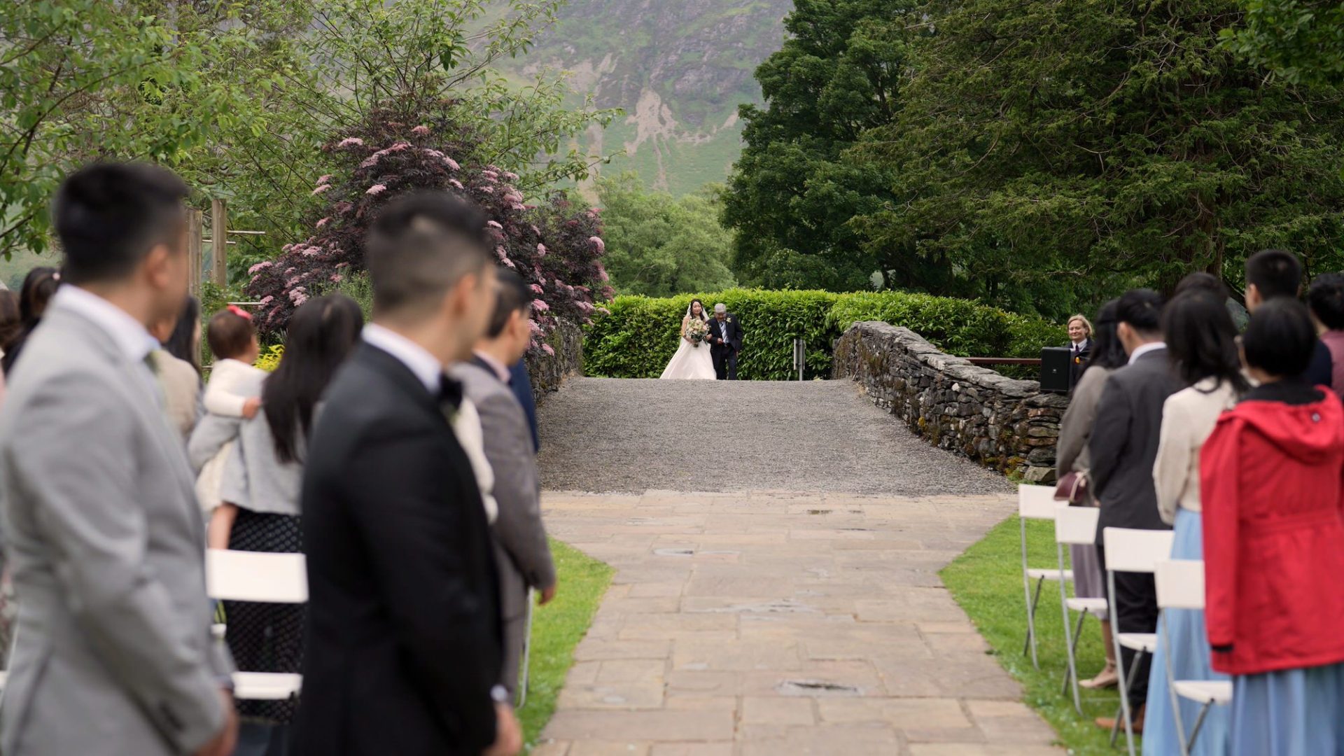 a bride walks across the stone bridge to the outside ceremony at lodore falls hotel
