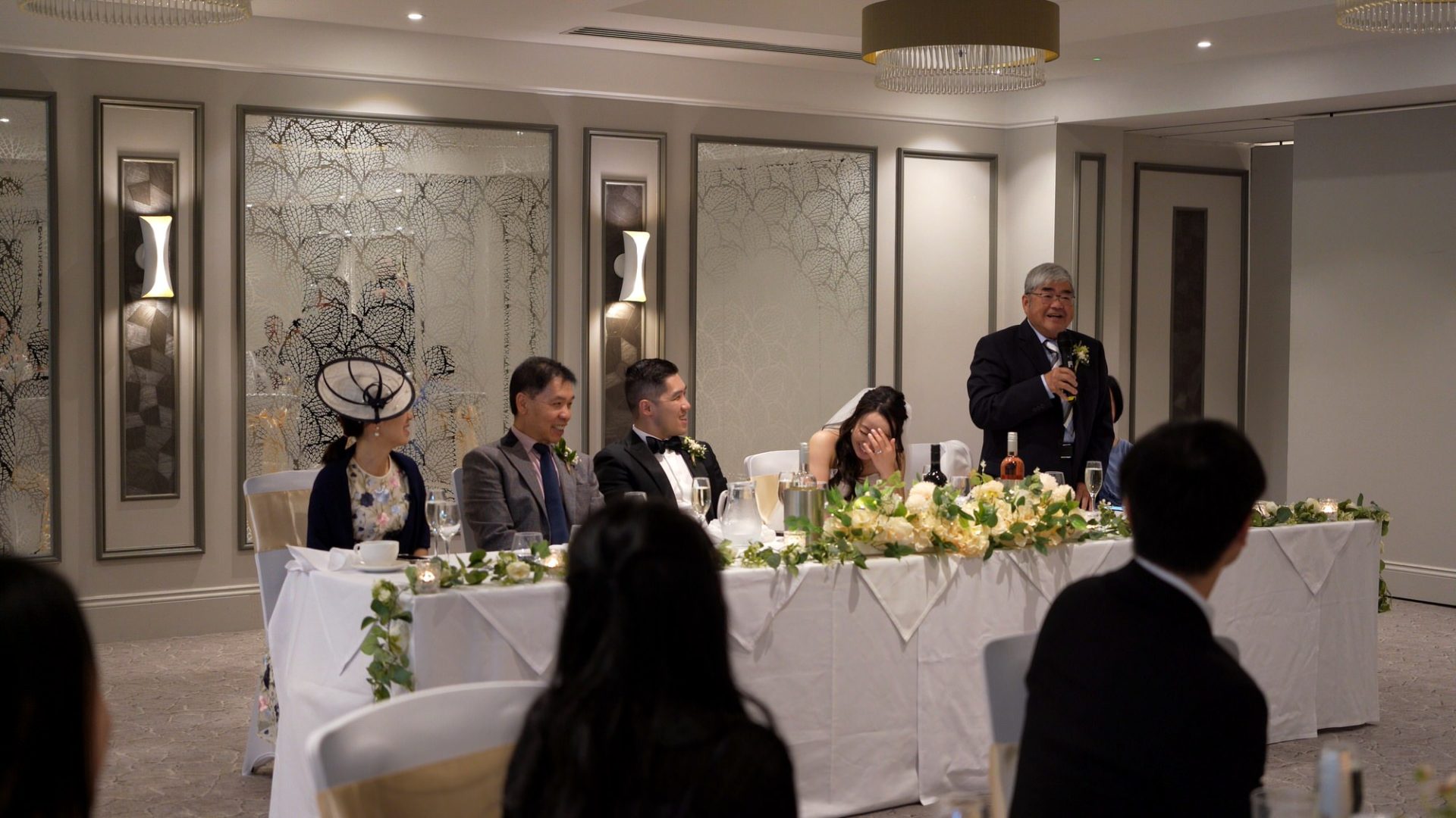 A Chinese Father of the bride stands to deliver his speech