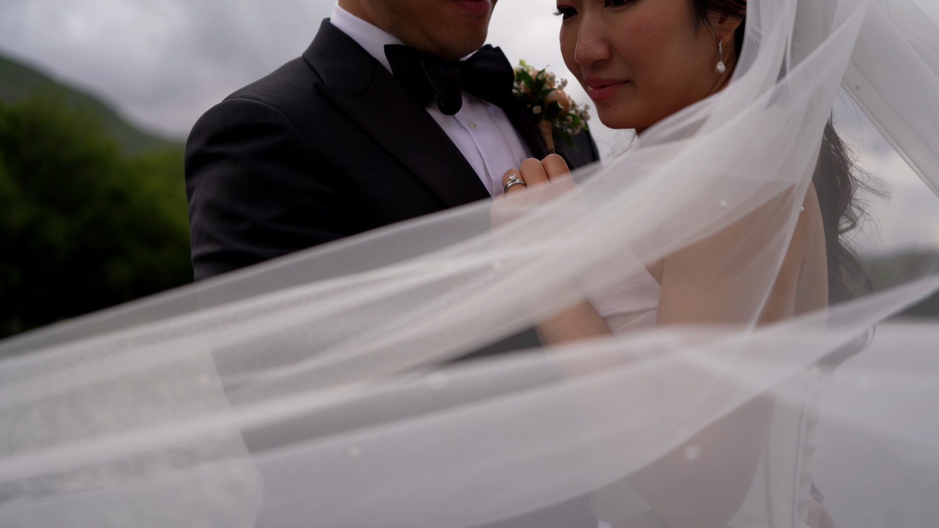 a close up video of a couple by derwentwater as the wind blows the veil