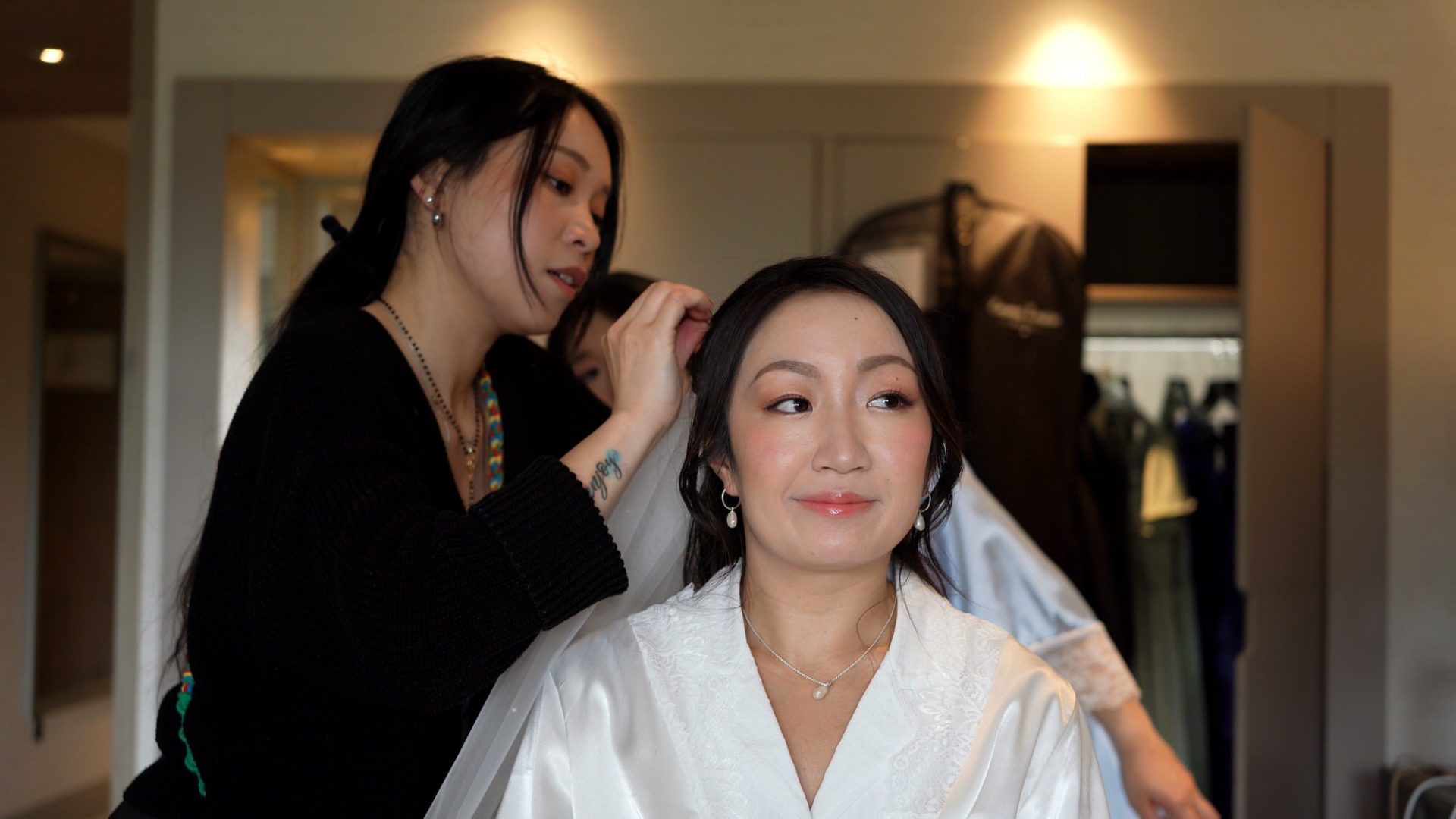 a bride sits on a bed at lodore whilst her veil is fitted