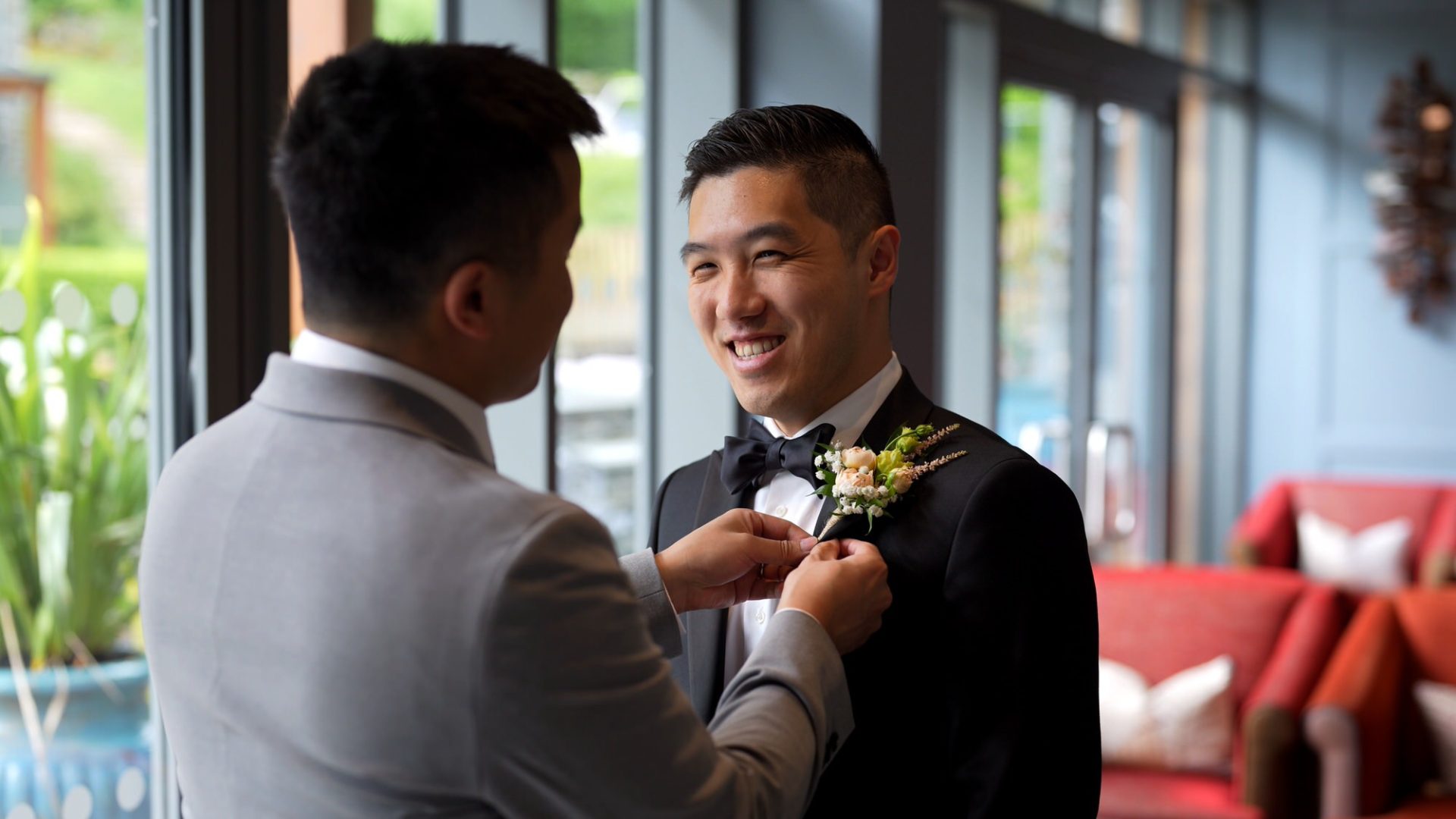 a groom in black tie suit gets his wedding button hole pinned