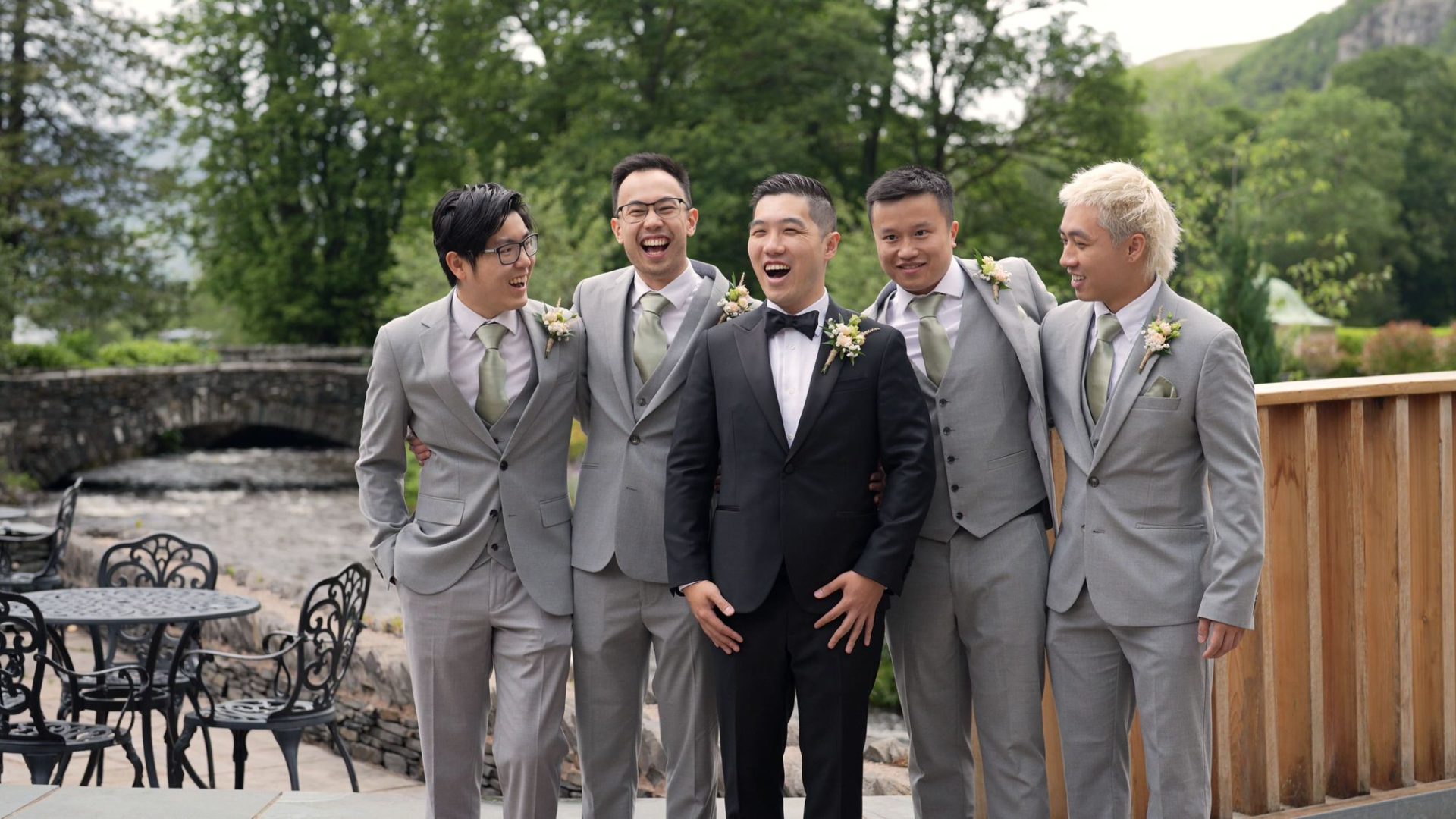 a groom in black tie with his groomsmen in grey suits outside lodore falls hotel