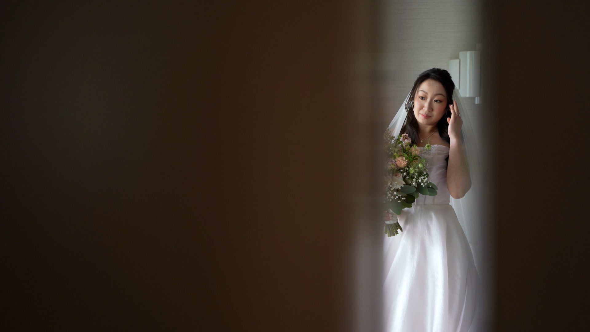 a candid shot of a bride through a gap in a door