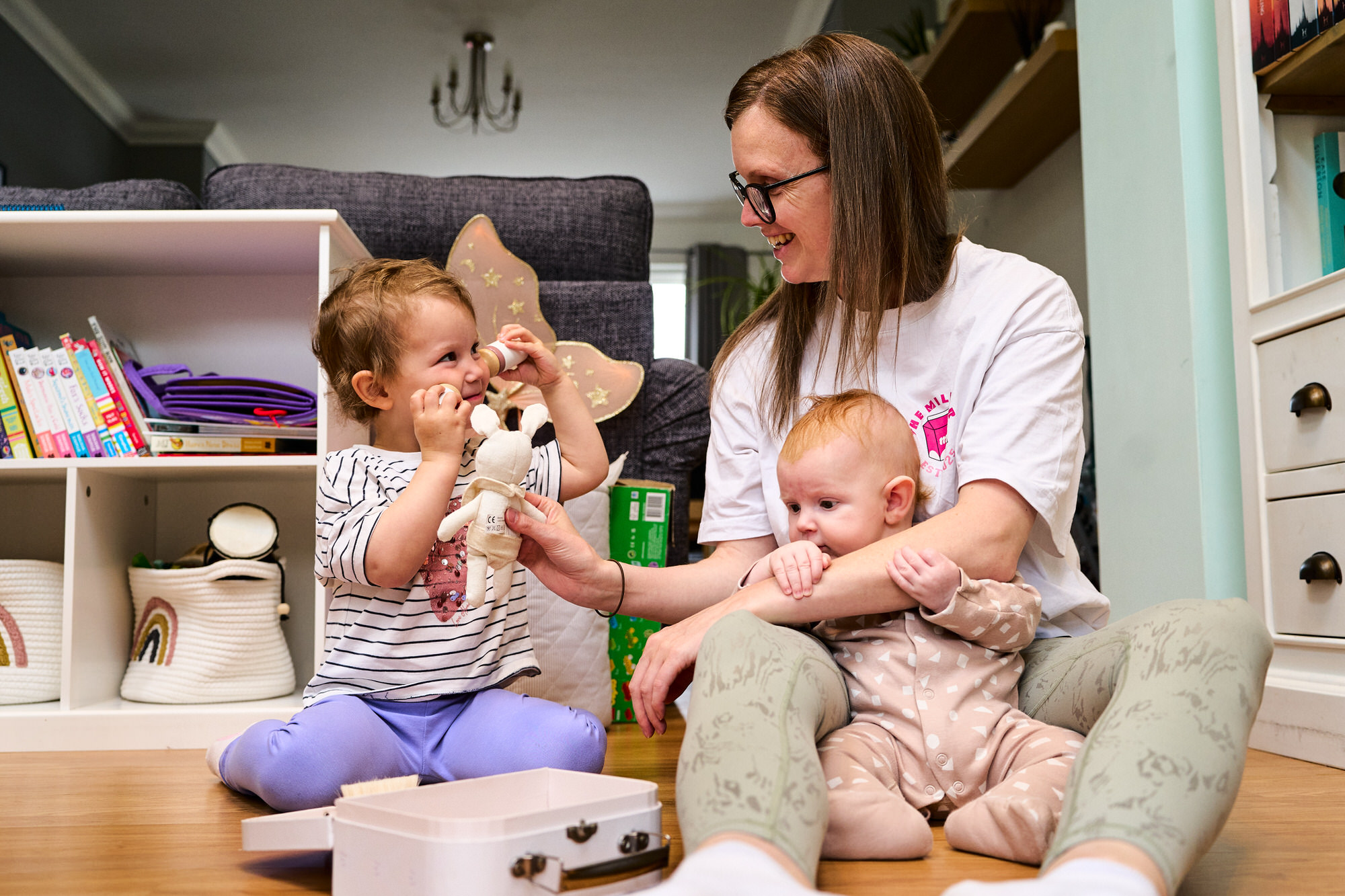 a mum sits on the floor with her baby and toddler to play