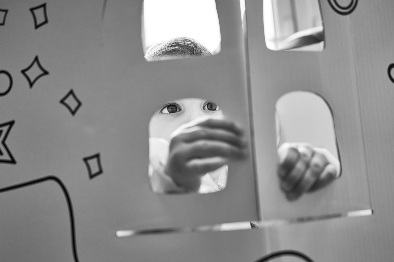 a little girl adjusts her windows in her handmade cardboard house