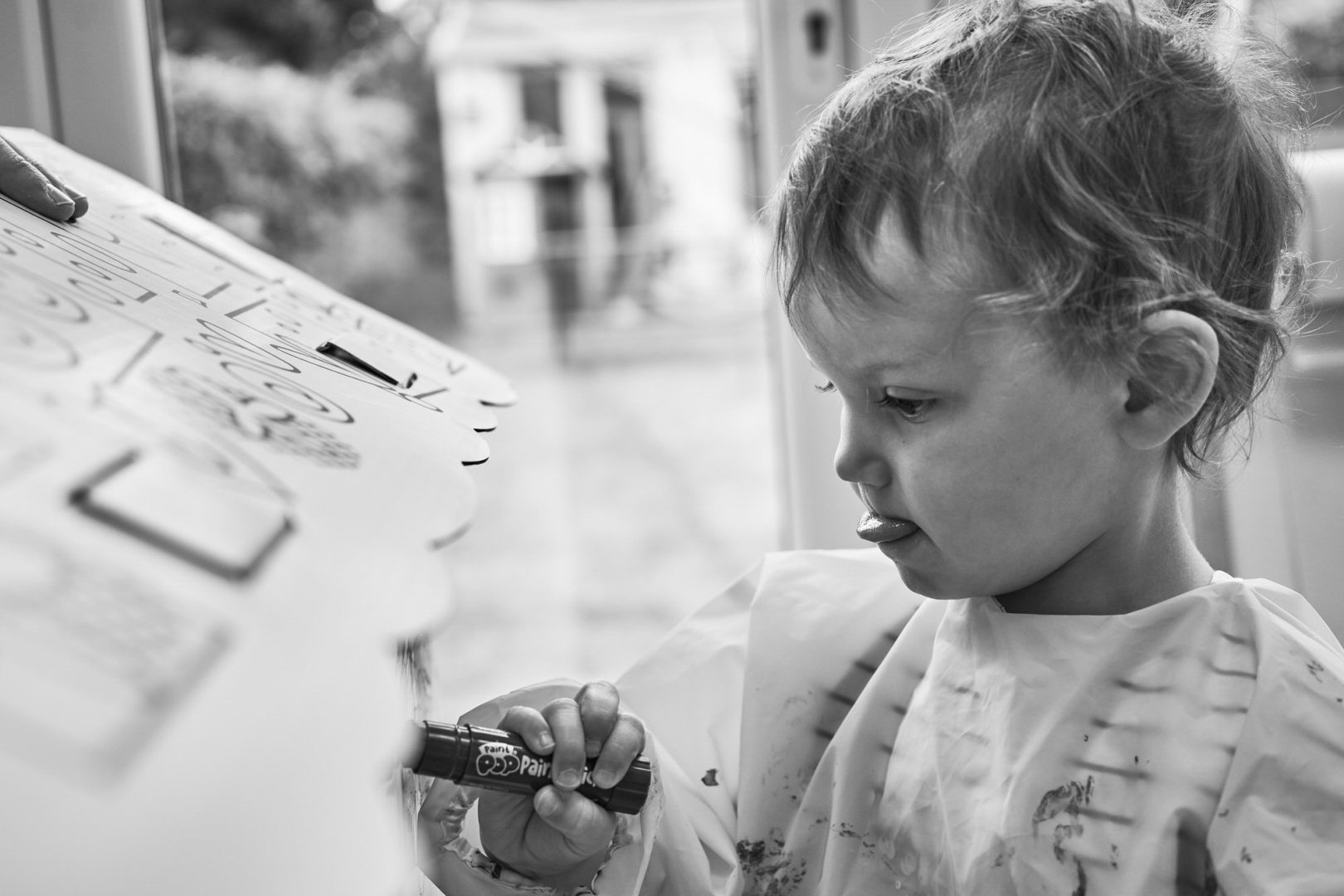 a candid photo of a child painting and sticking their concentration tongue out